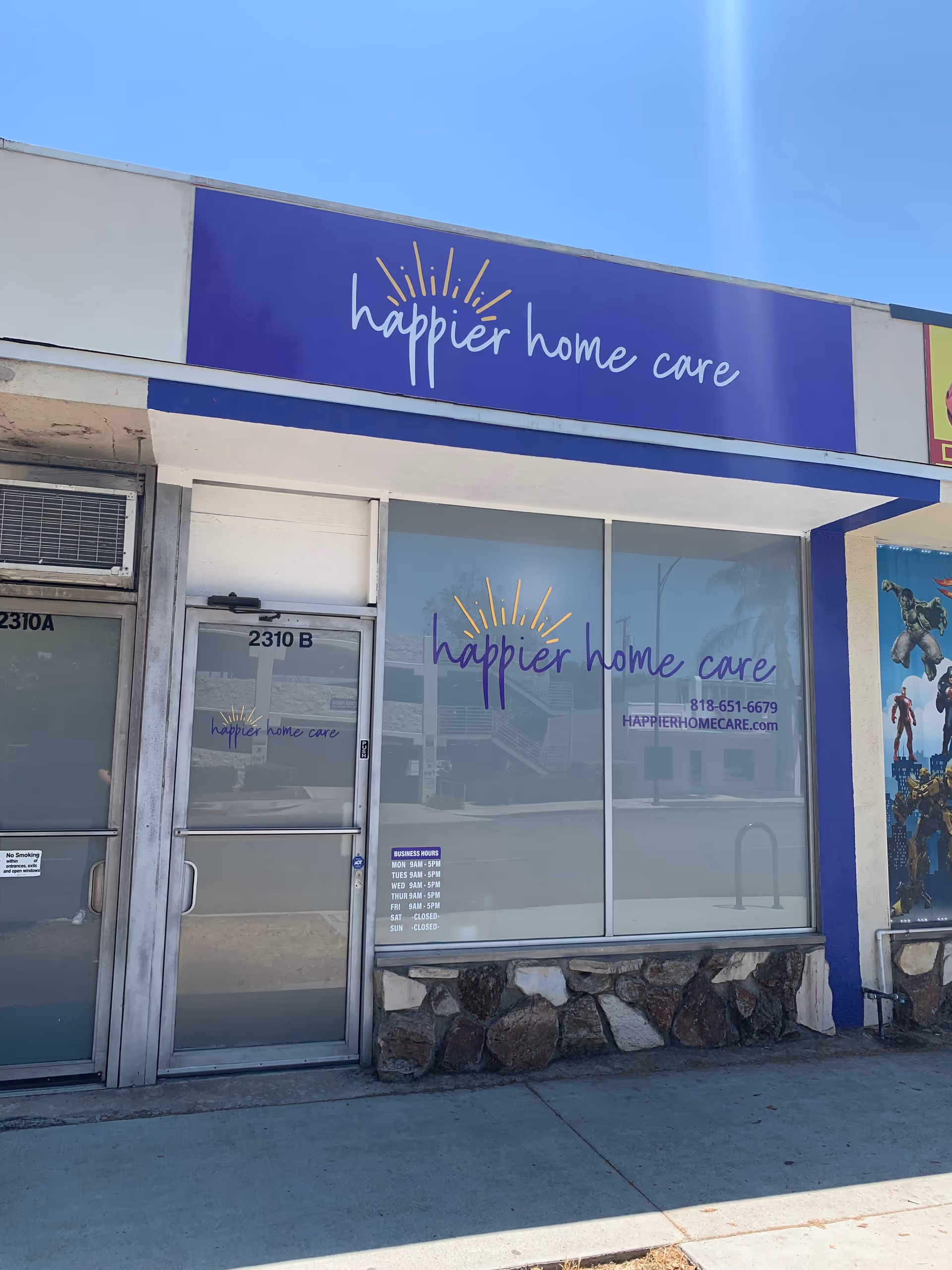 Storefront of Happier Home Care with purple sign on building exterior.