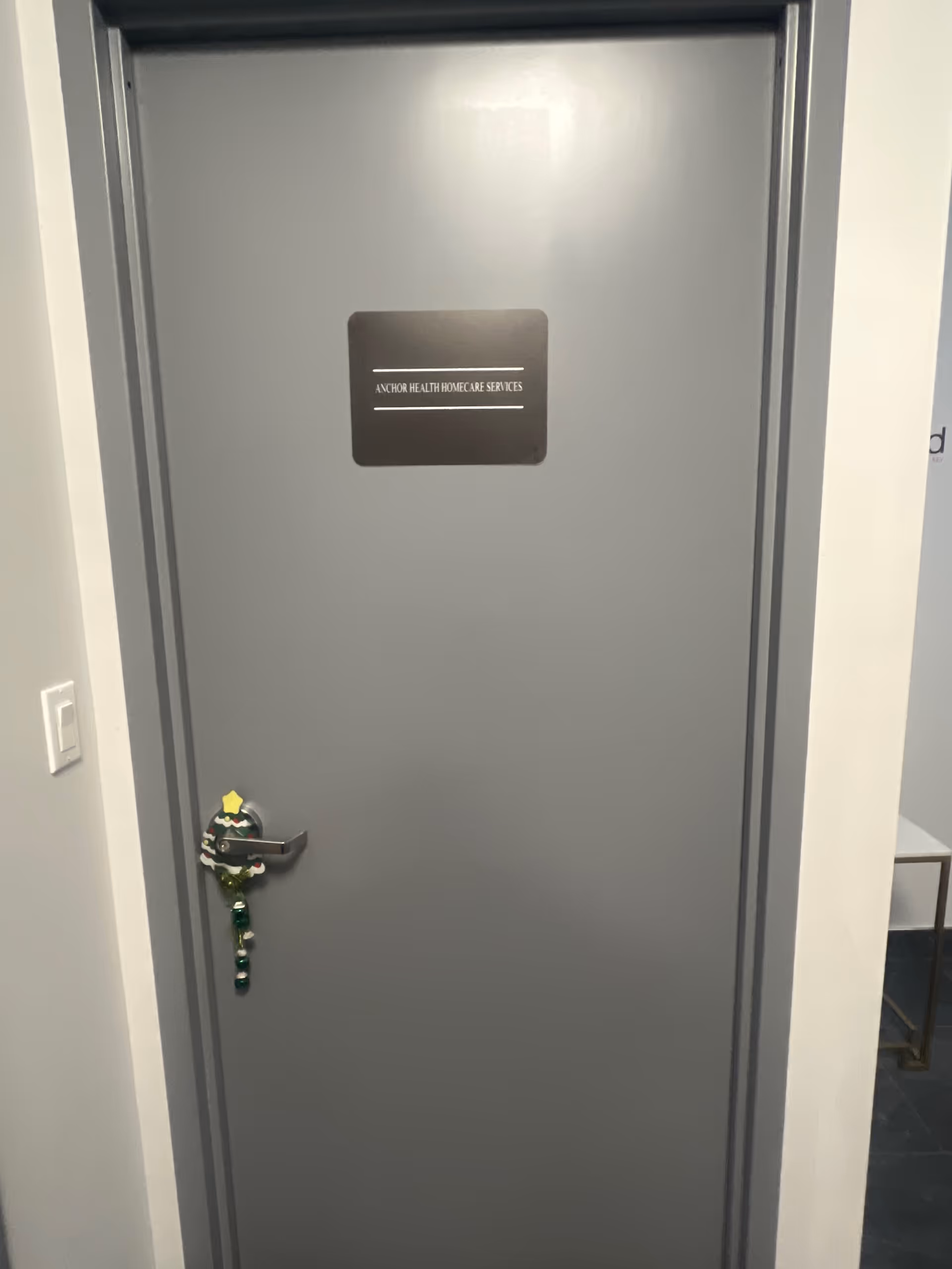 Grey interior door with Anchor Health Homecare Services sign and hanging decoration in hallway