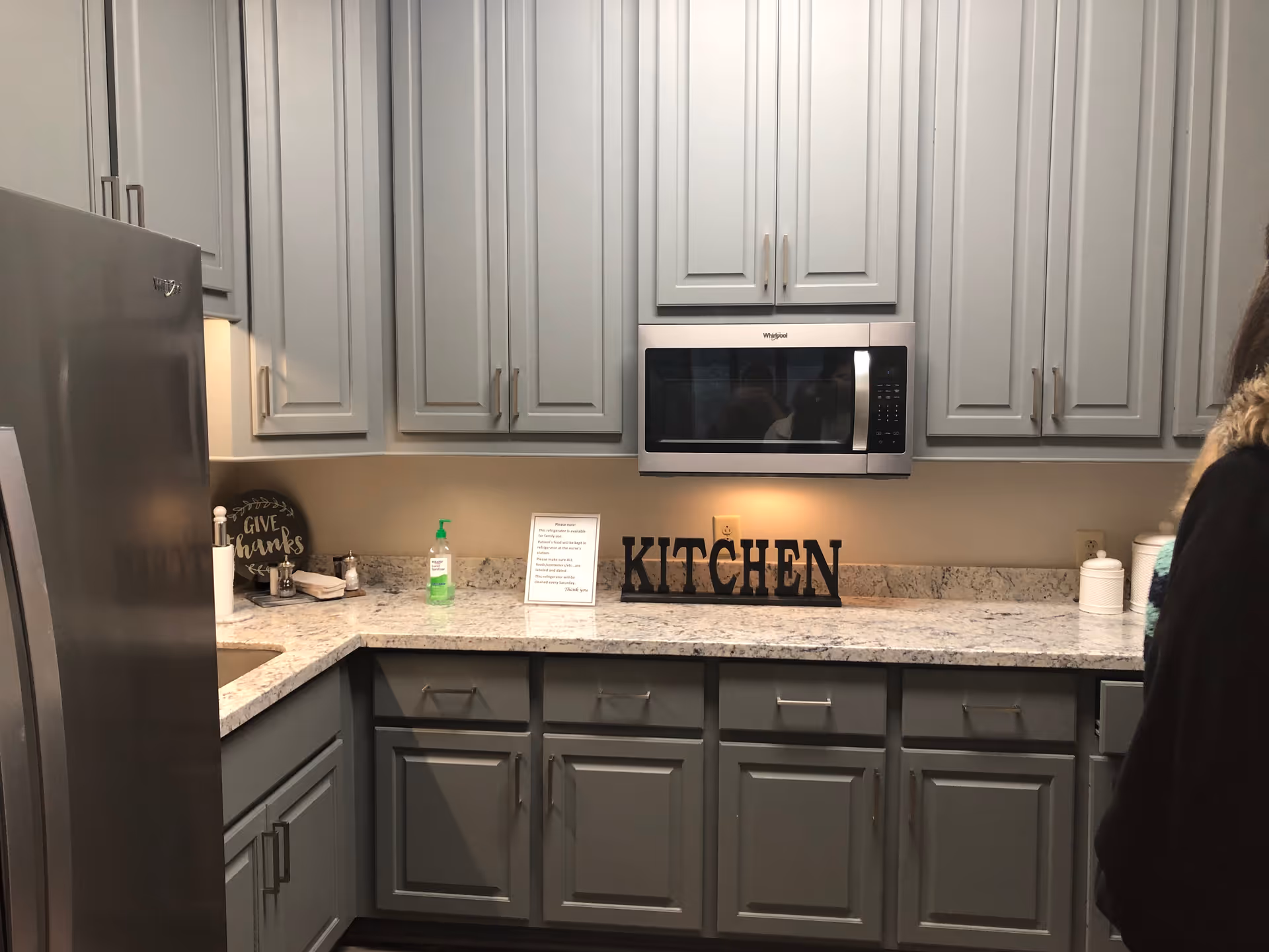 Grey kitchen with granite countertops, light cabinets, and a microwave above the counter.