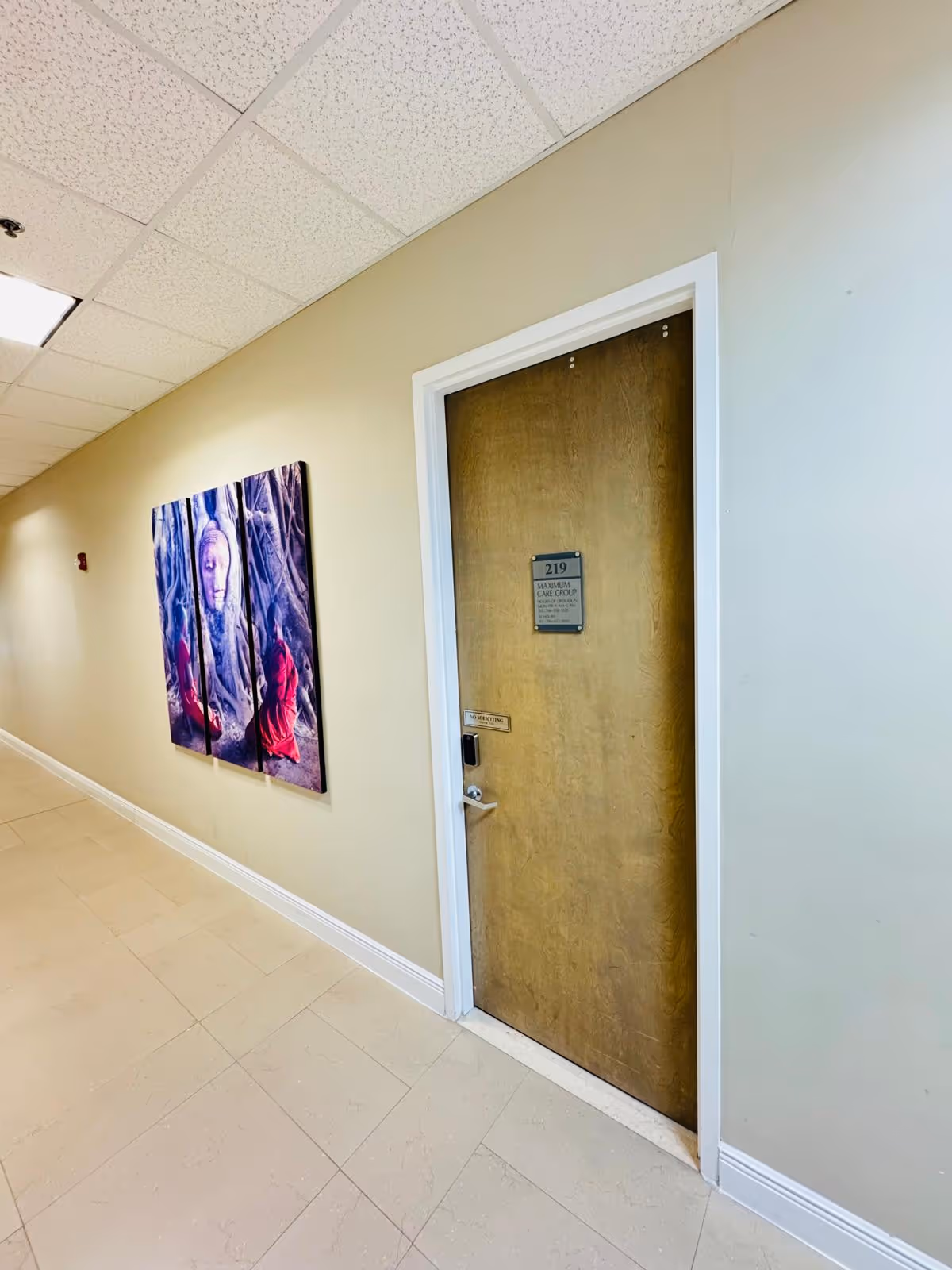 Cream hallway with a wooden door labeled 219 and wall art panels.