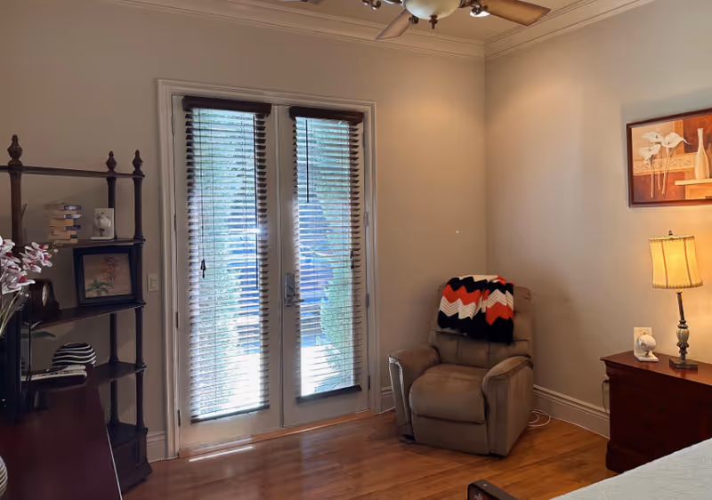 Cozy senior living room in a Royal Palms Care Home with blinds and a recliner.
