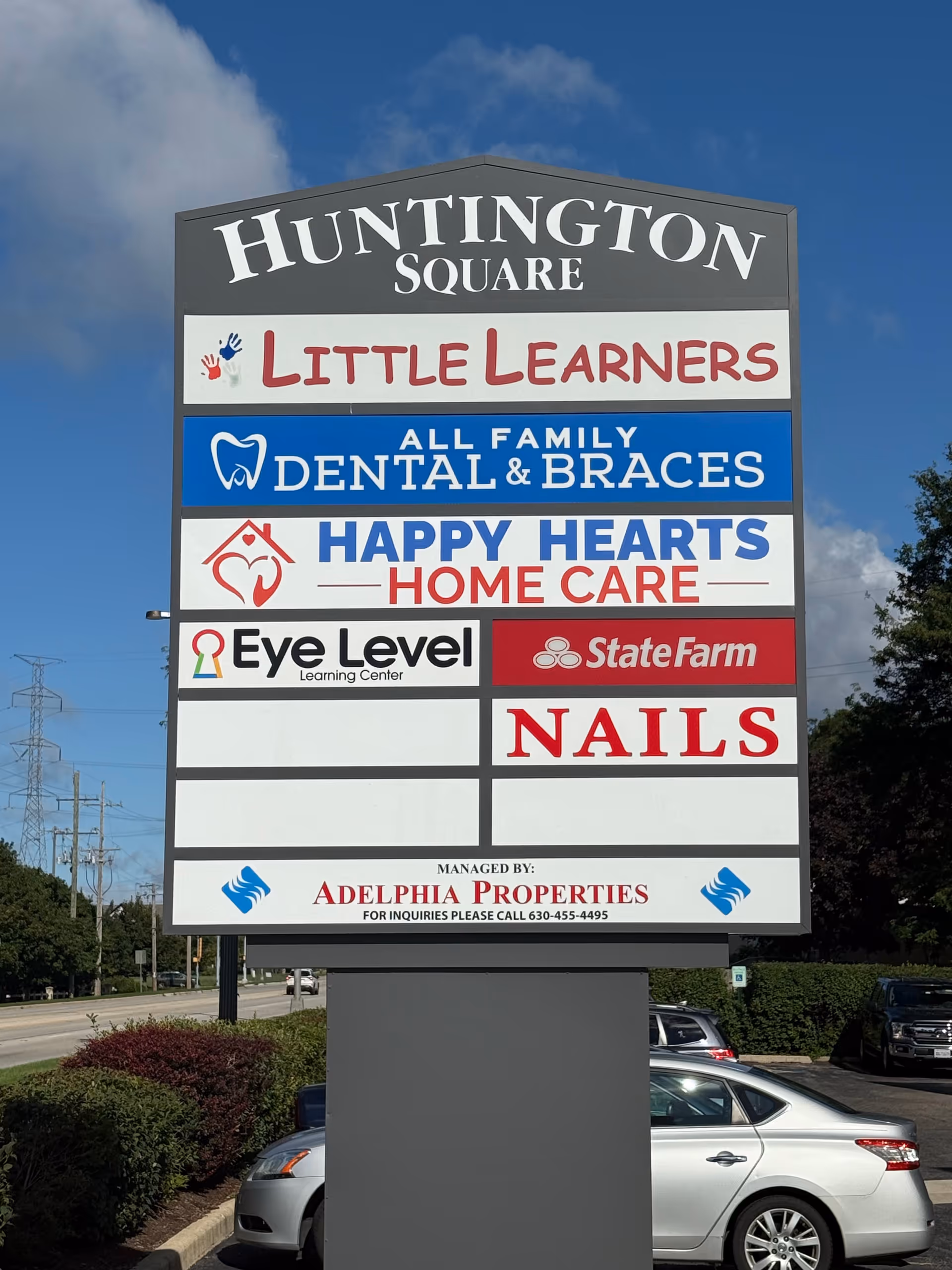 Outdoor signboard listing Huntington Square tenants, including Happy Hearts Home Care.