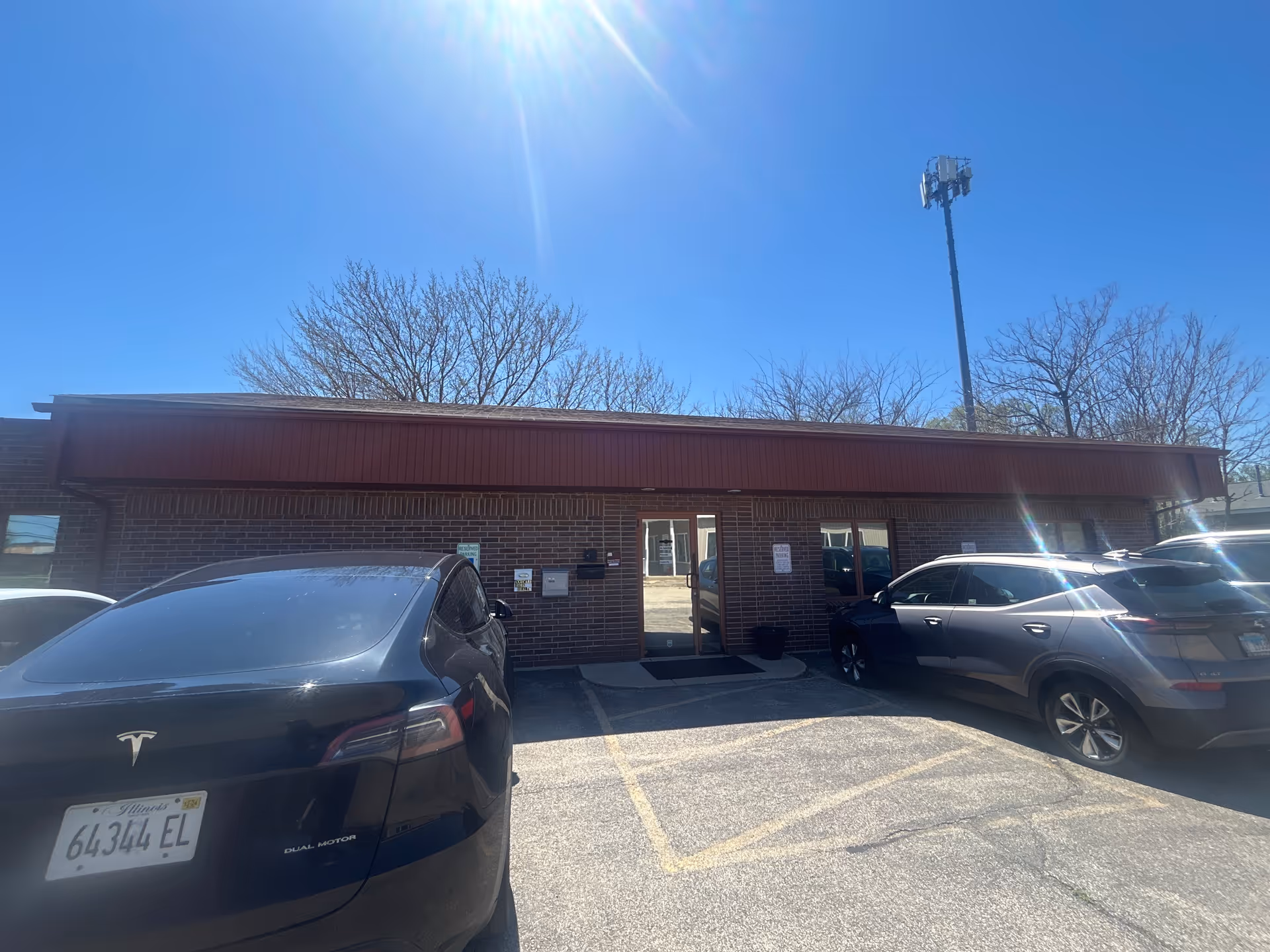 Brick building with a red awning and parked cars in front.