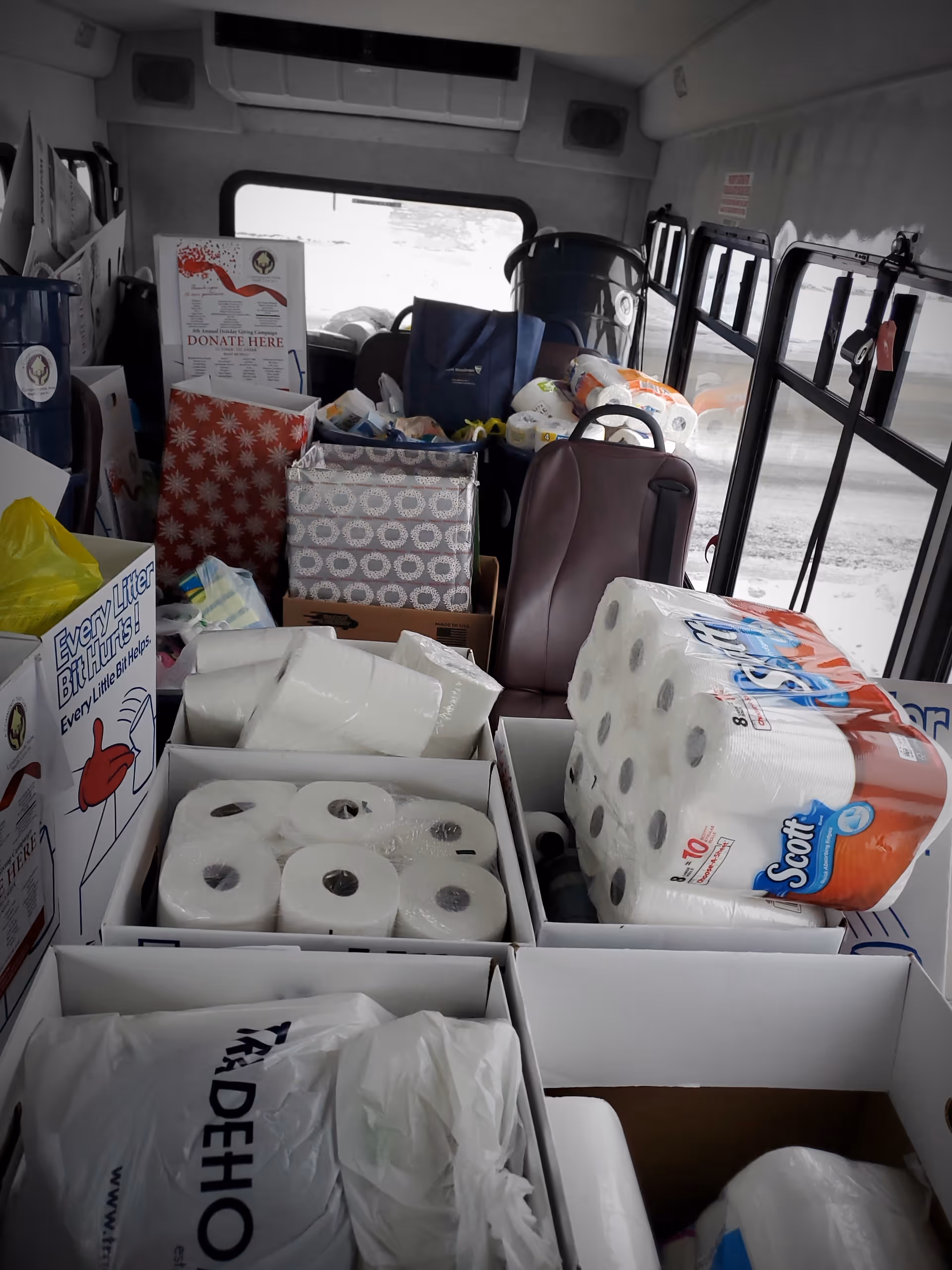 Interior of a donation vehicle filled with boxes of toilet paper and supplies.