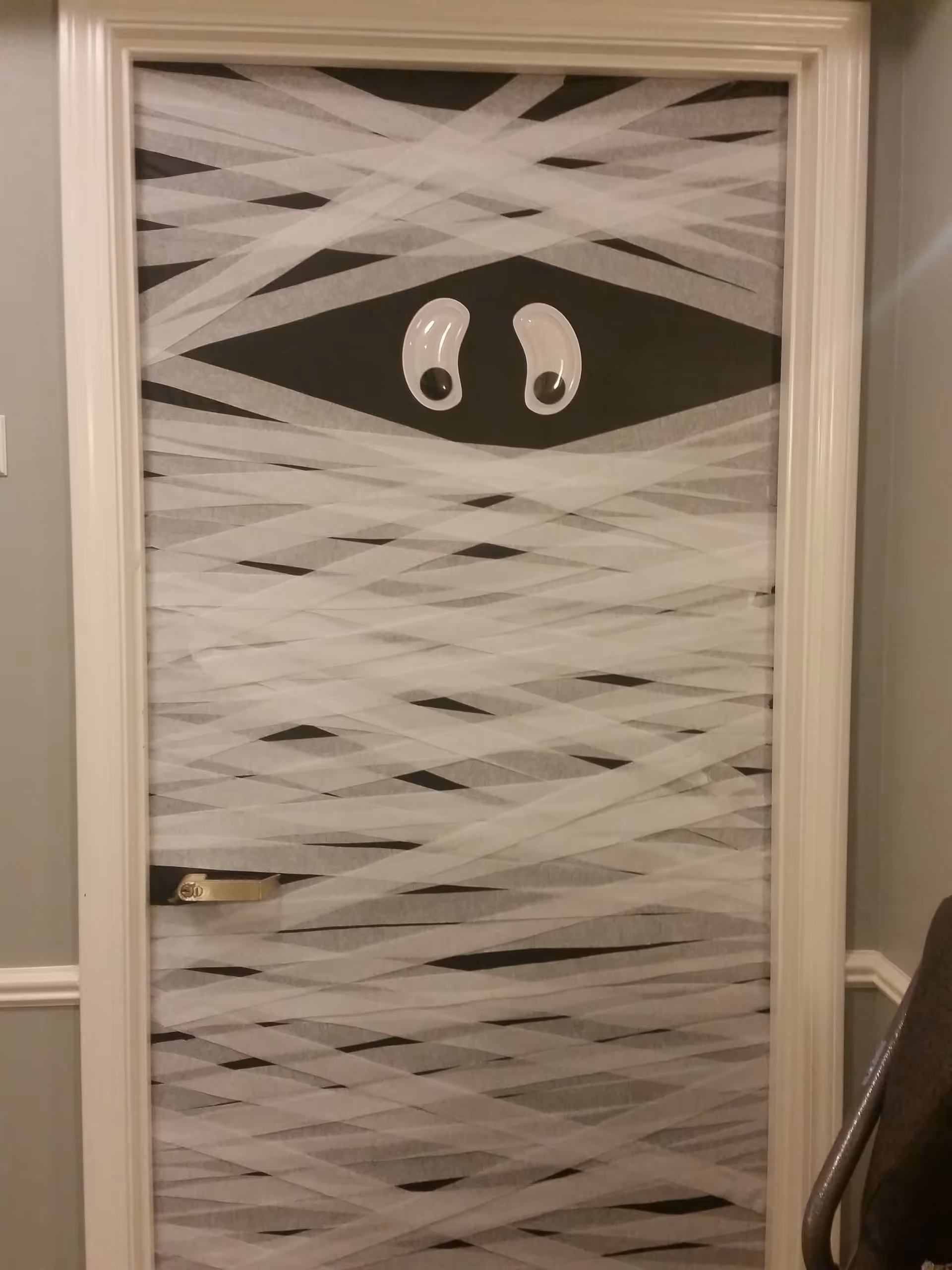 An interior door wrapped in a diagonal pattern with cartoon eyes.