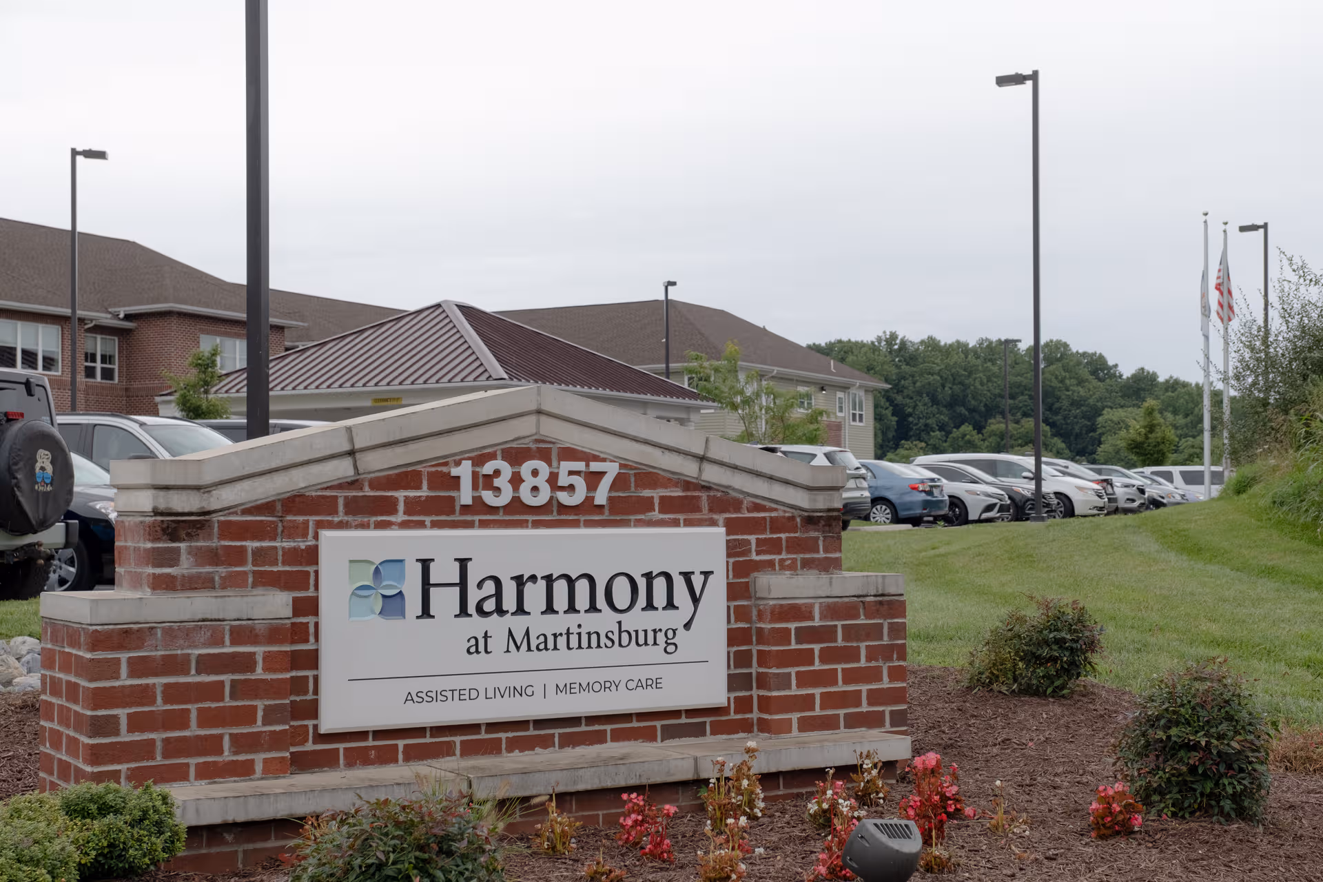 Exterior brick sign for Harmony at Martinsburg with a parking lot in the background.