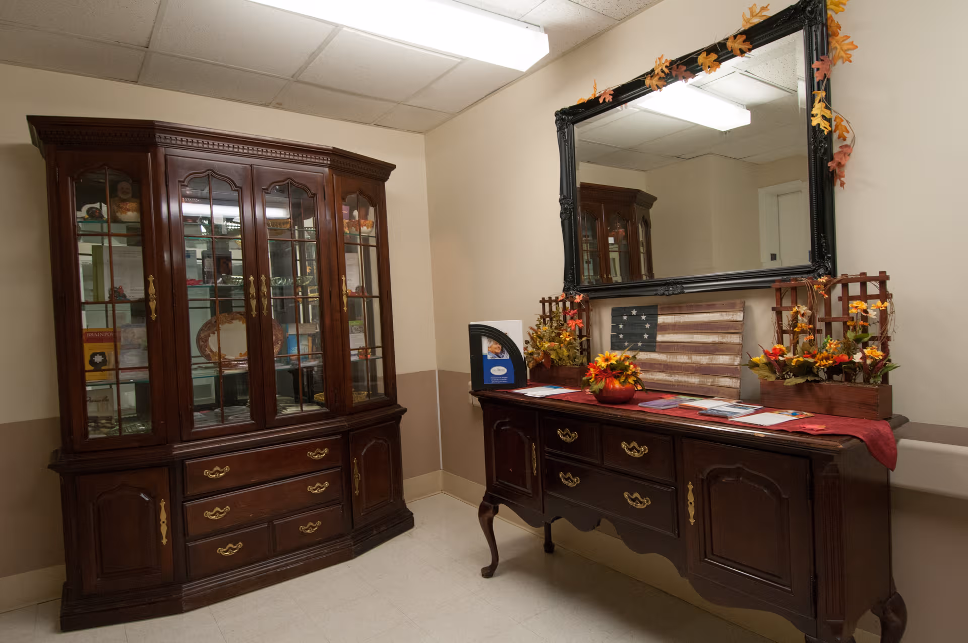 Dimly lit, classic wooden cabinet and dresser with mirror decorate a quiet senior living interior.