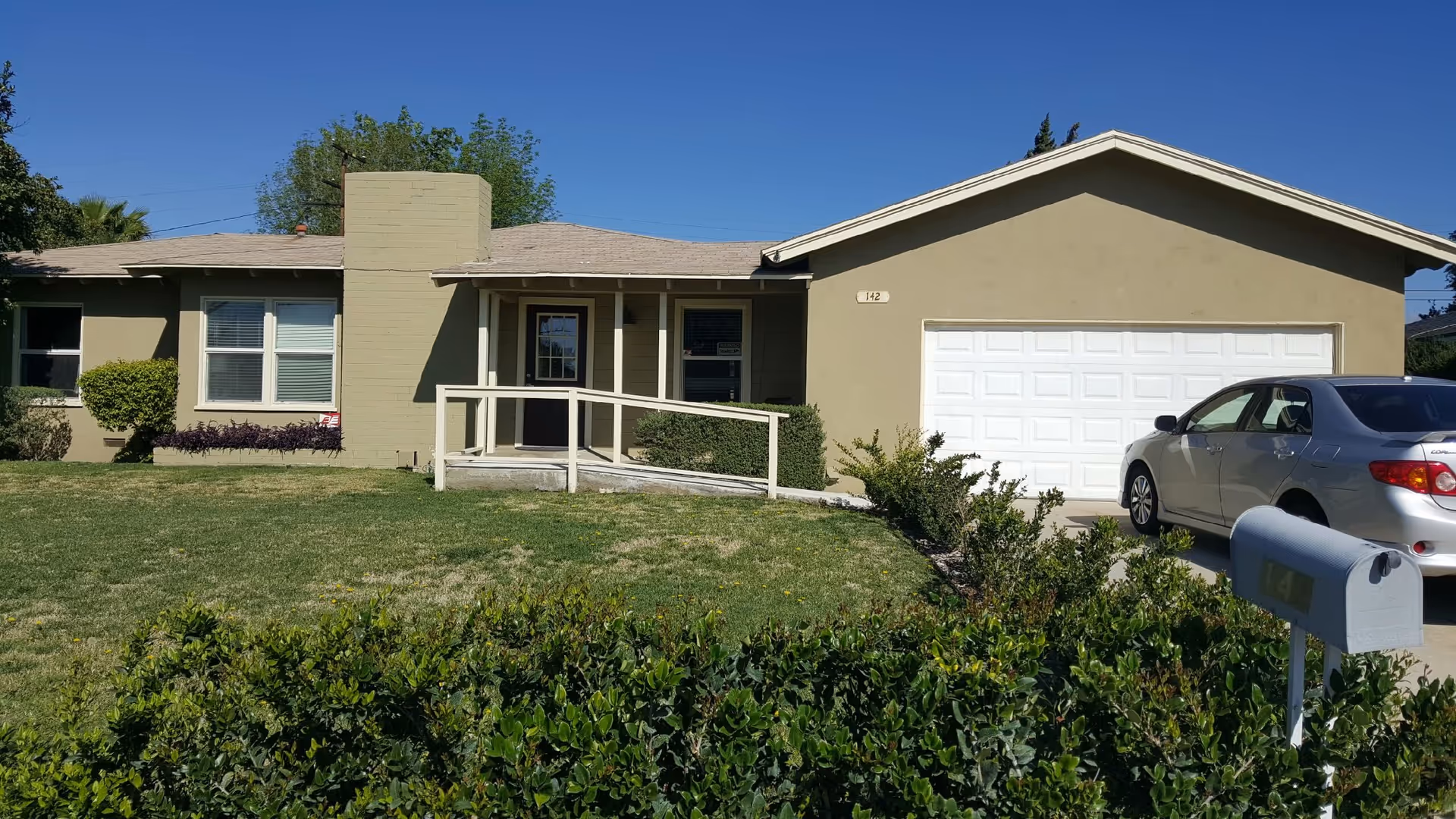 Exterior view of Rialto Assisted Living, a single-story building with ramp, driveway, and parked car.