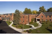 Exterior view of a brick senior living facility with curved walkways and green lawns.