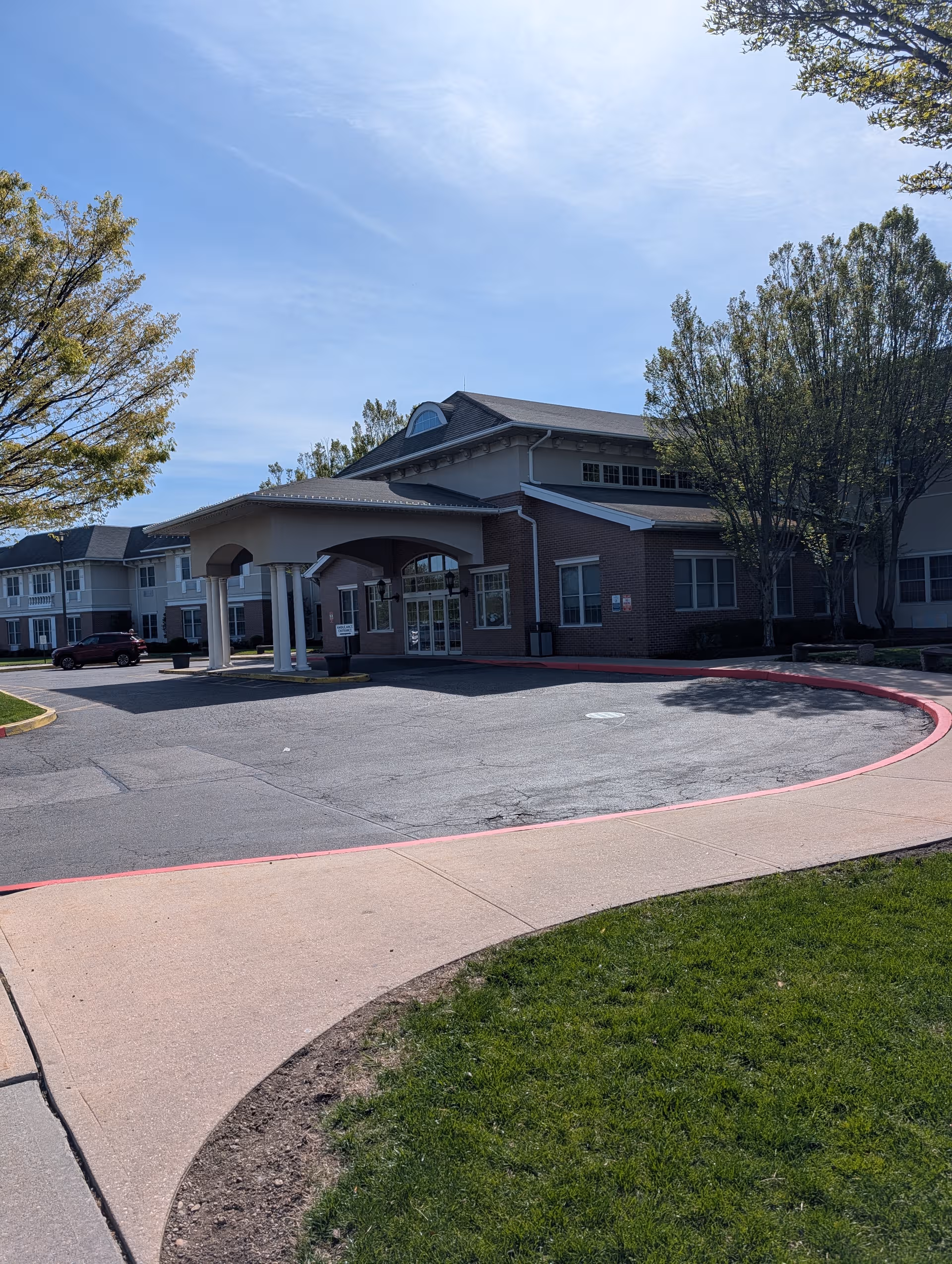 Exterior view of Huntington Hills Center showing brick building, entrance canopy, parking lot, and trees.