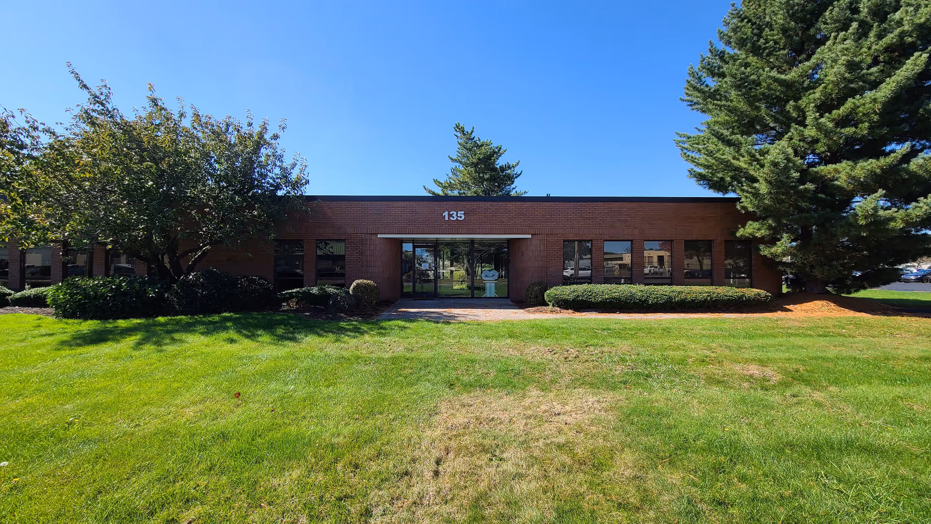 Brick senior care facility front entrance with glass doors and green lawn