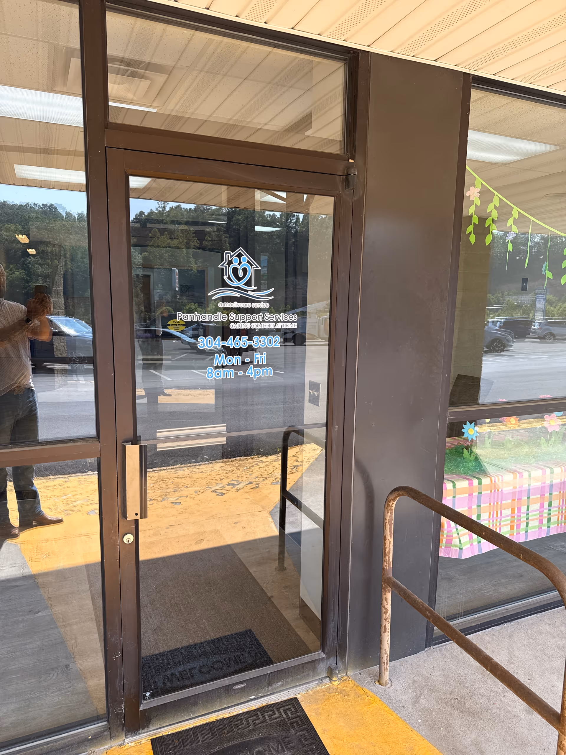 Glass front entrance with Panhandle Support Services logo and reflection of a person taking photo.