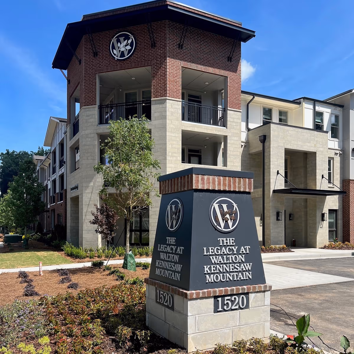 Modern senior living building exterior with brick facade and prominent entry sign.