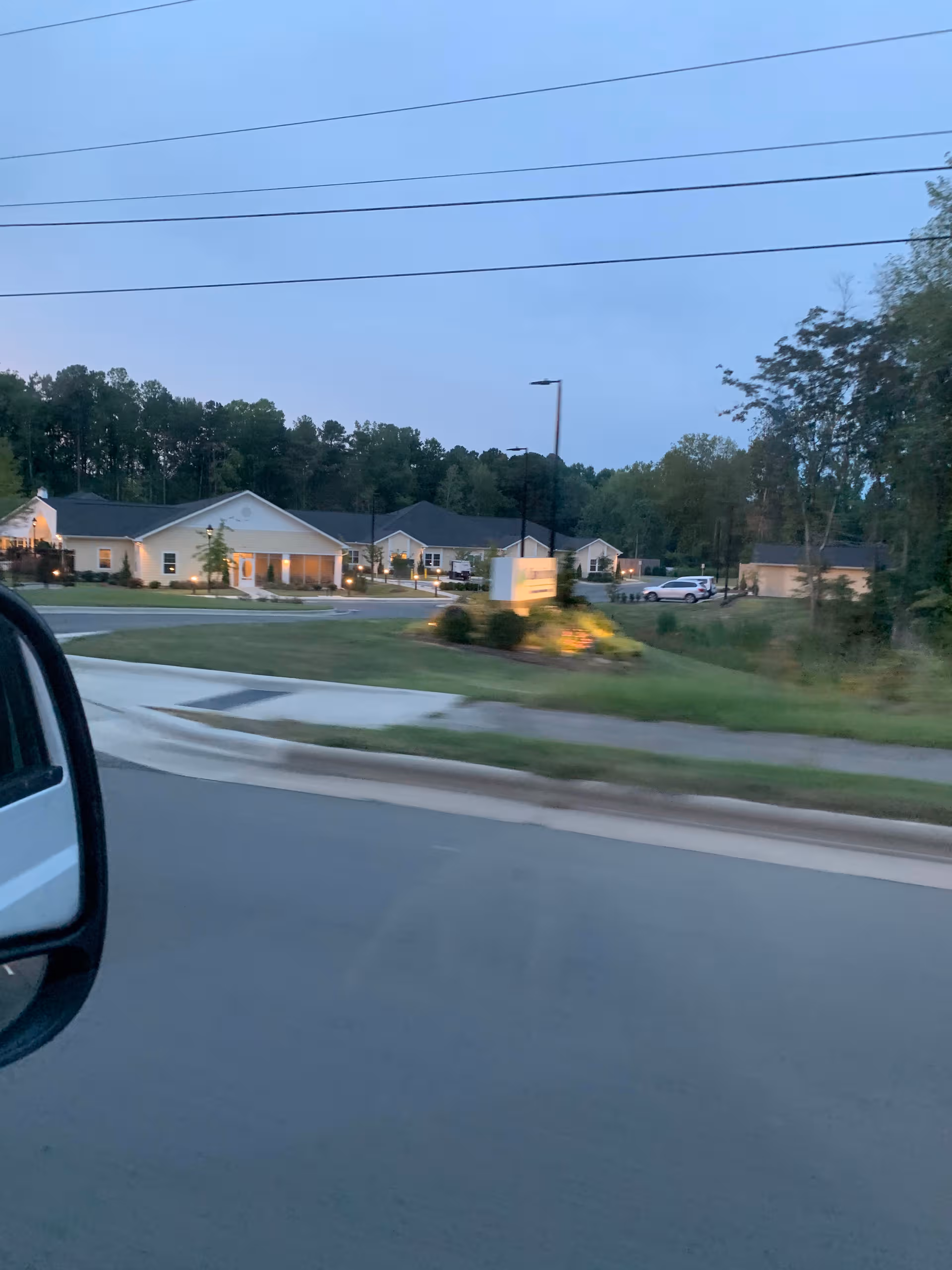 Exterior view of Calyx Living of Durham with a lit front entrance and surrounding lawn.