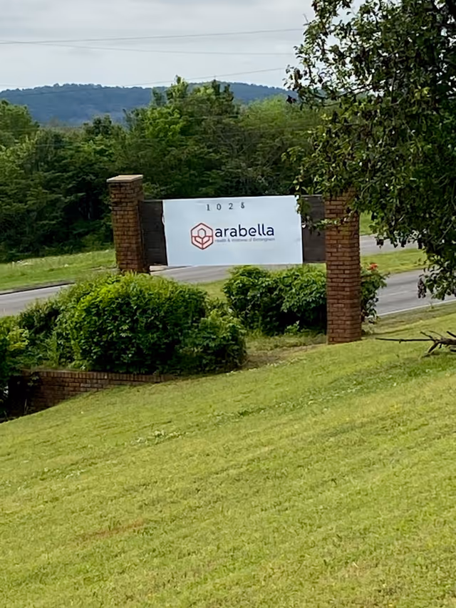 Brick entrance pillars frame a white sign reading Arabella near manicured grass.