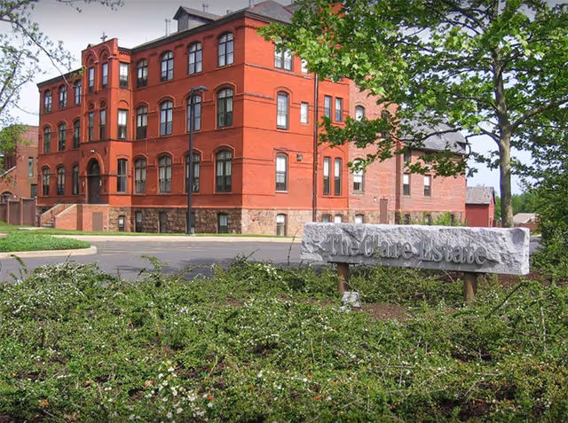Red brick senior living building with a stone sign reading The Clare Estate