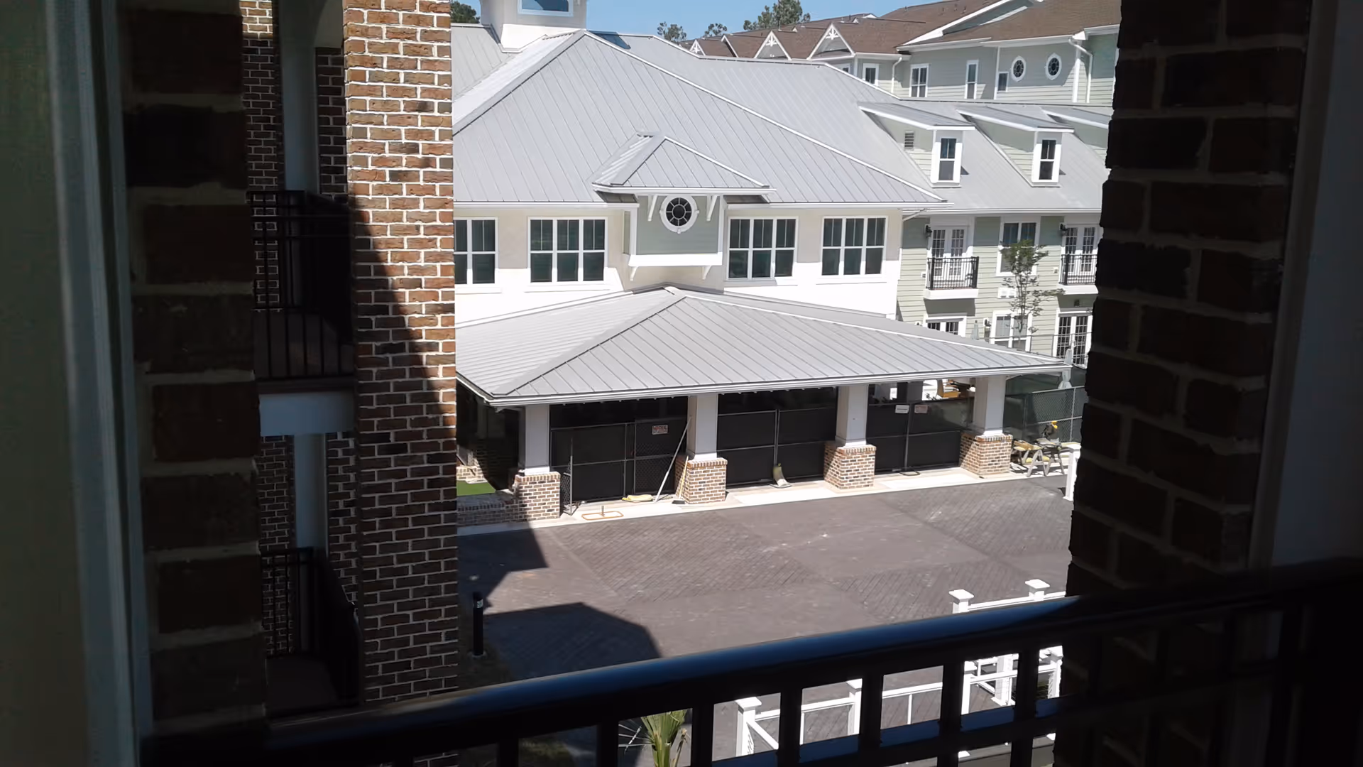 Exterior view of a Cambridge Village residential complex with brick columns and metal-roofed buildings.