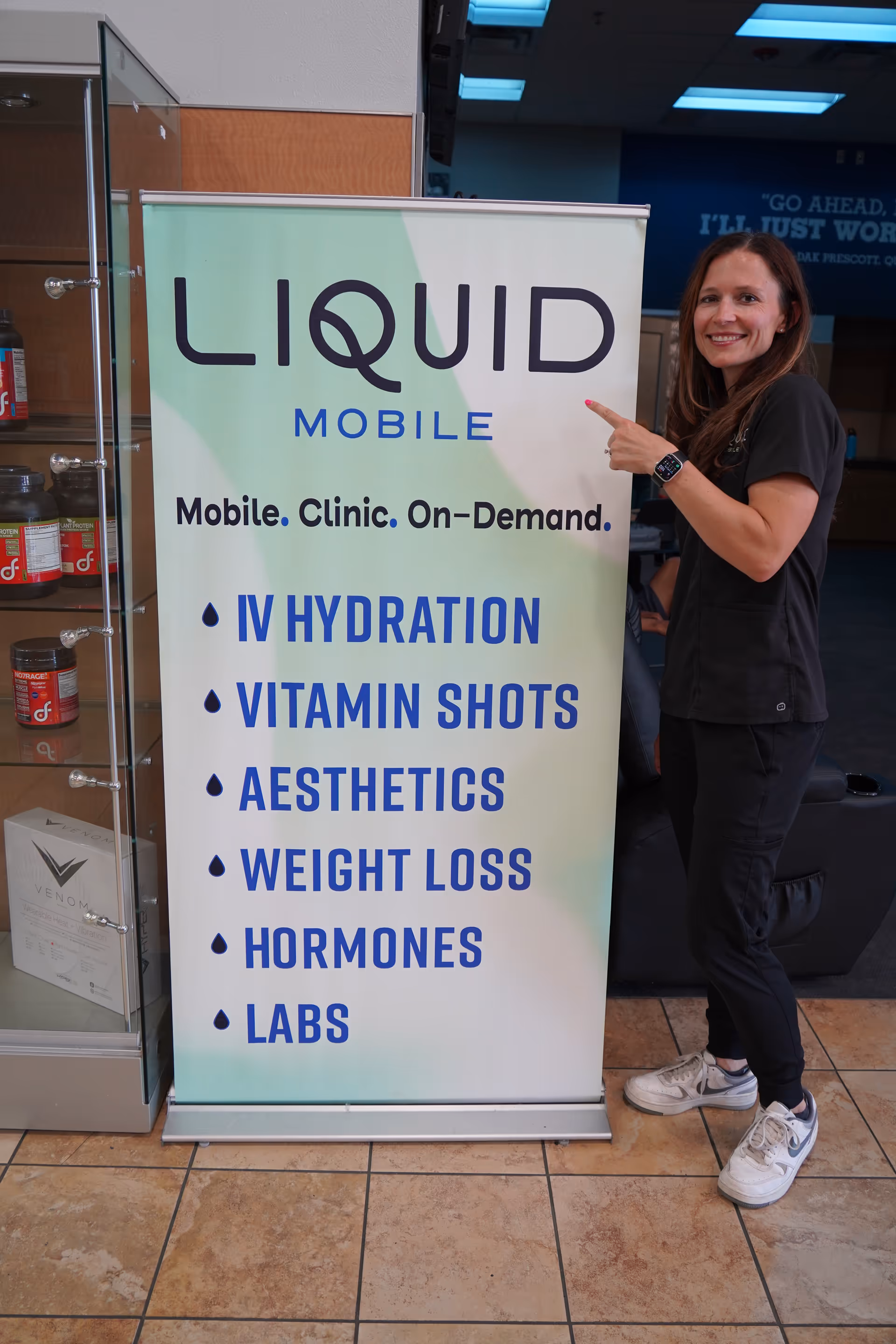 Liquid Mobile IV banner indoors beside a smiling staff member.