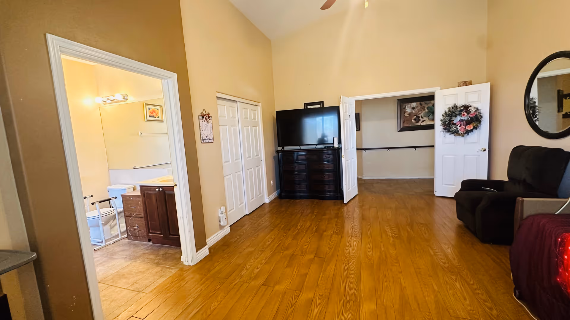 Living room with wood floors, a recliner, TV, and open doors to adjacent spaces.