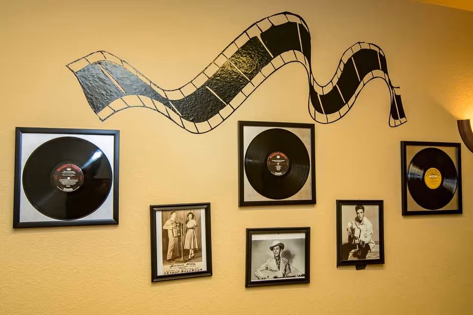 Wall decorated with framed vinyl records, vintage black-and-white photos, and a painted filmstrip mural.