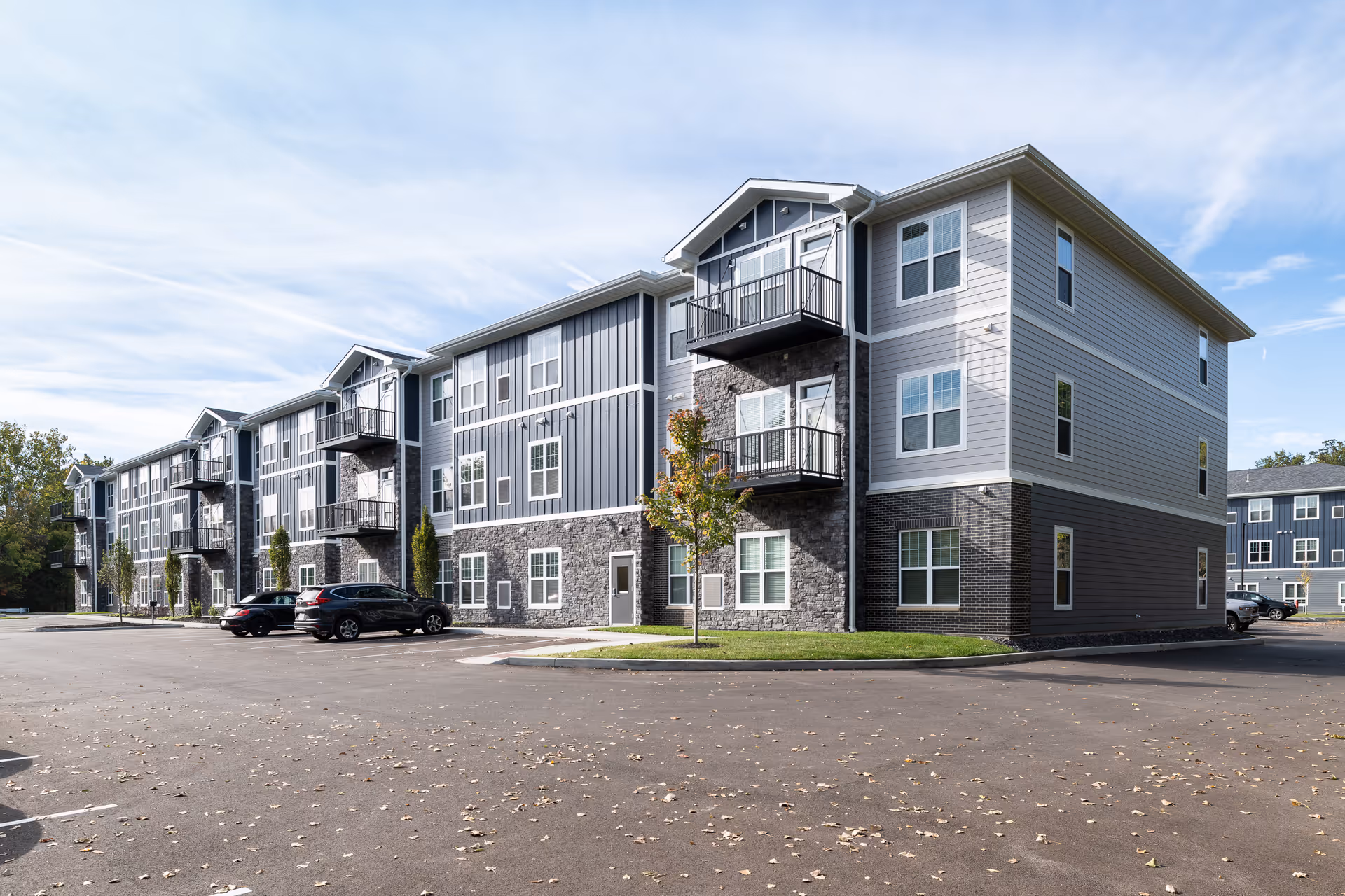 A modern senior living apartment complex with balconies, stone accents, and a parking lot.
