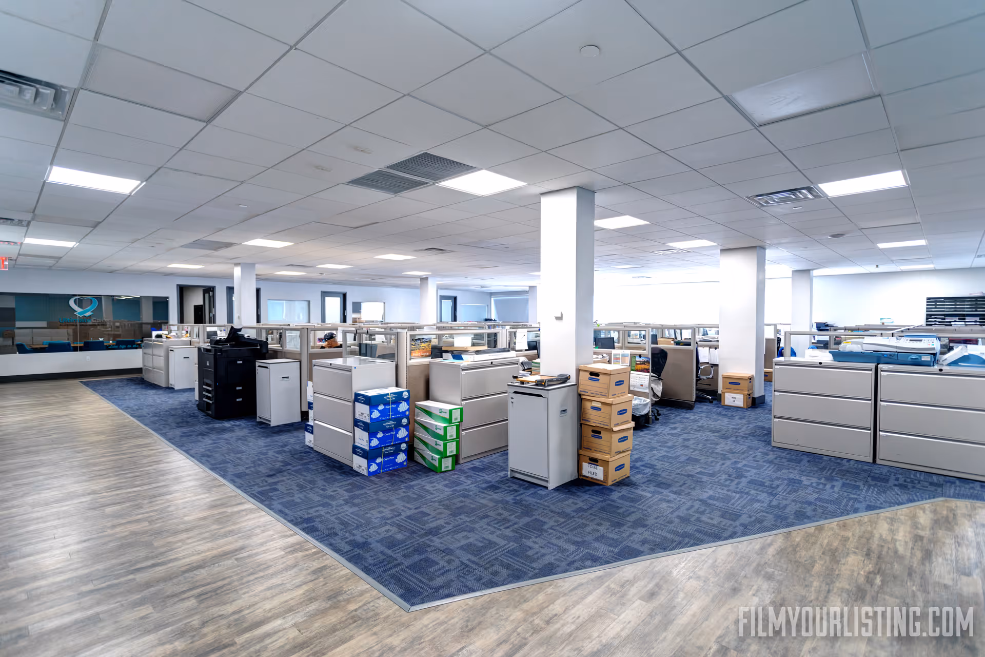 Senior living facility admin area with cubicles, printers, and storage boxes.