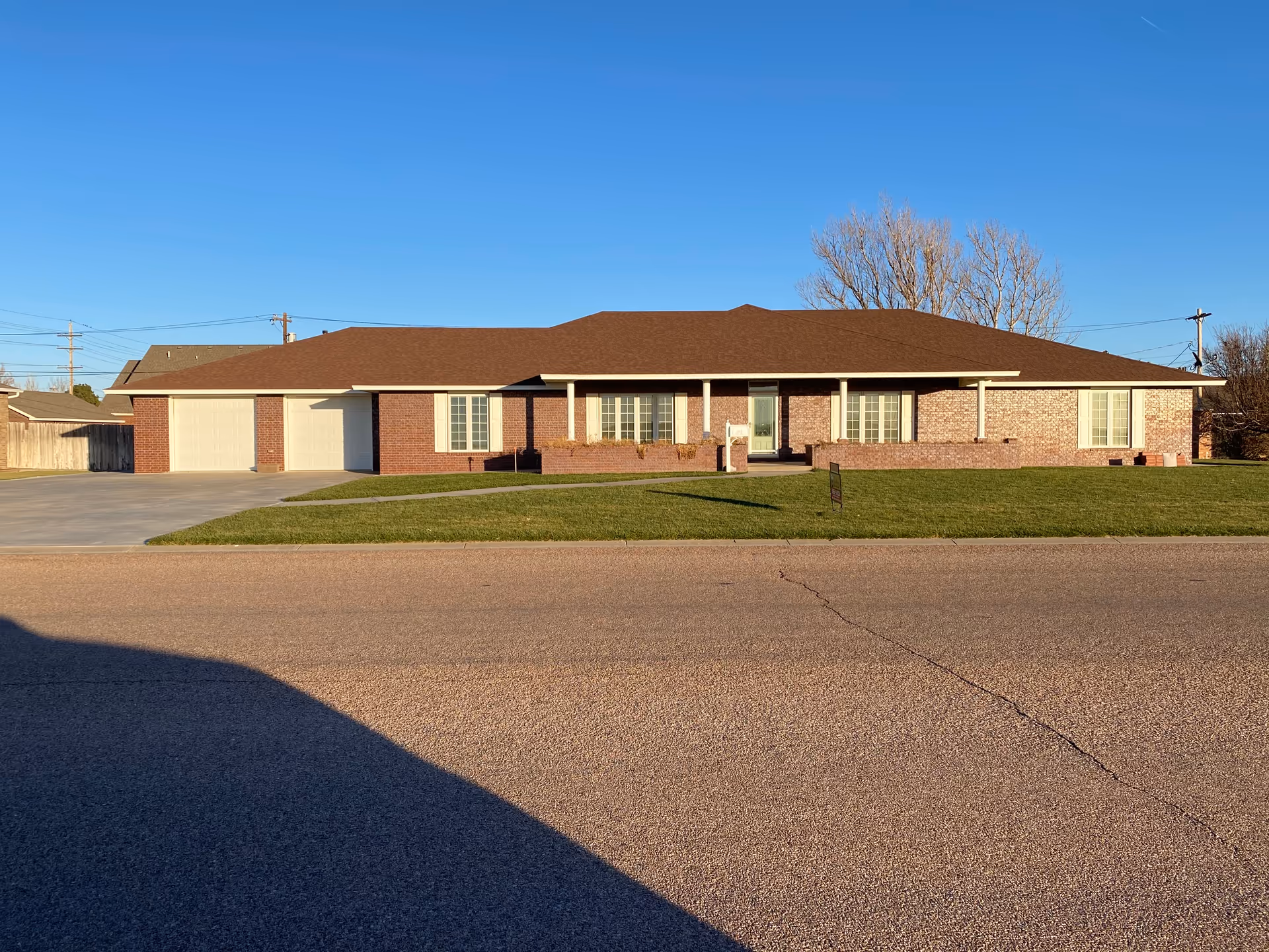 Single-story brick facility with front entrance, wide driveway, and manicured lawn under a clear blue sky.
