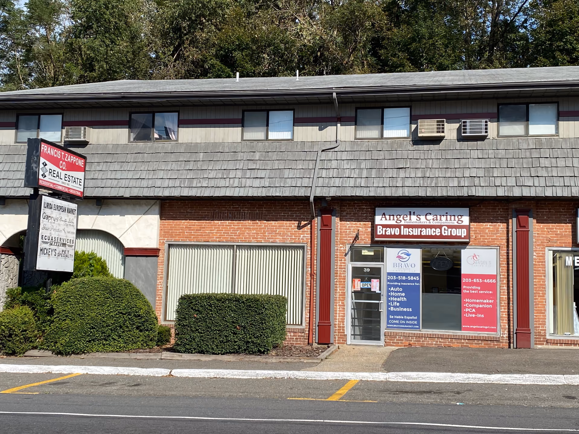 Exterior storefront with Angel's Caring LLC signage and Bravo Insurance Group ads.