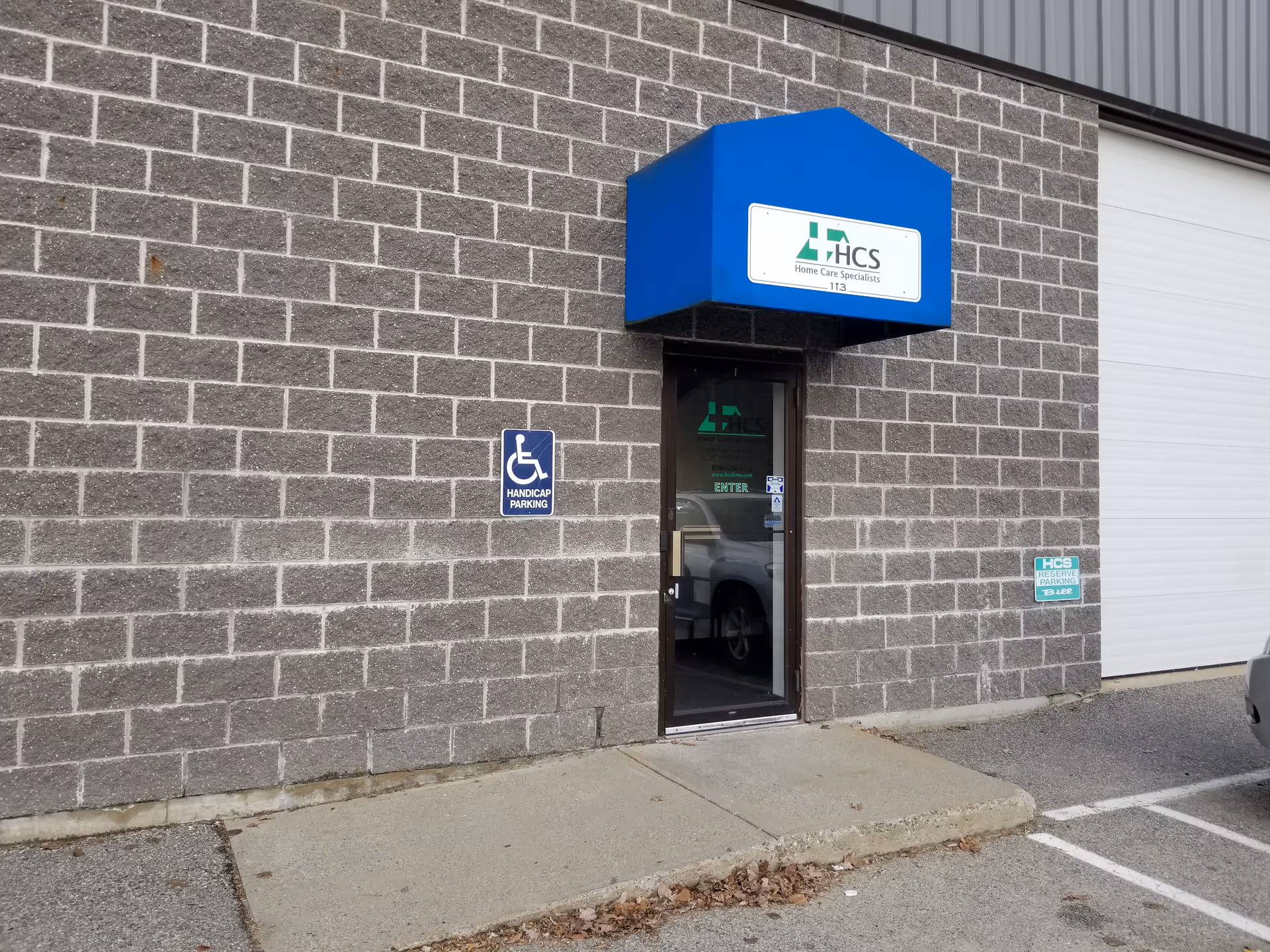 Brick exterior with a blue canopy over a glass entrance labeled HCS
