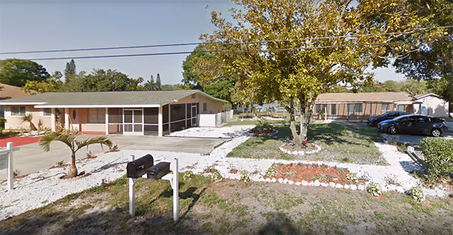 Single-story Select Group Homes exterior with front entrance, landscaped yard, bench, and parked cars.