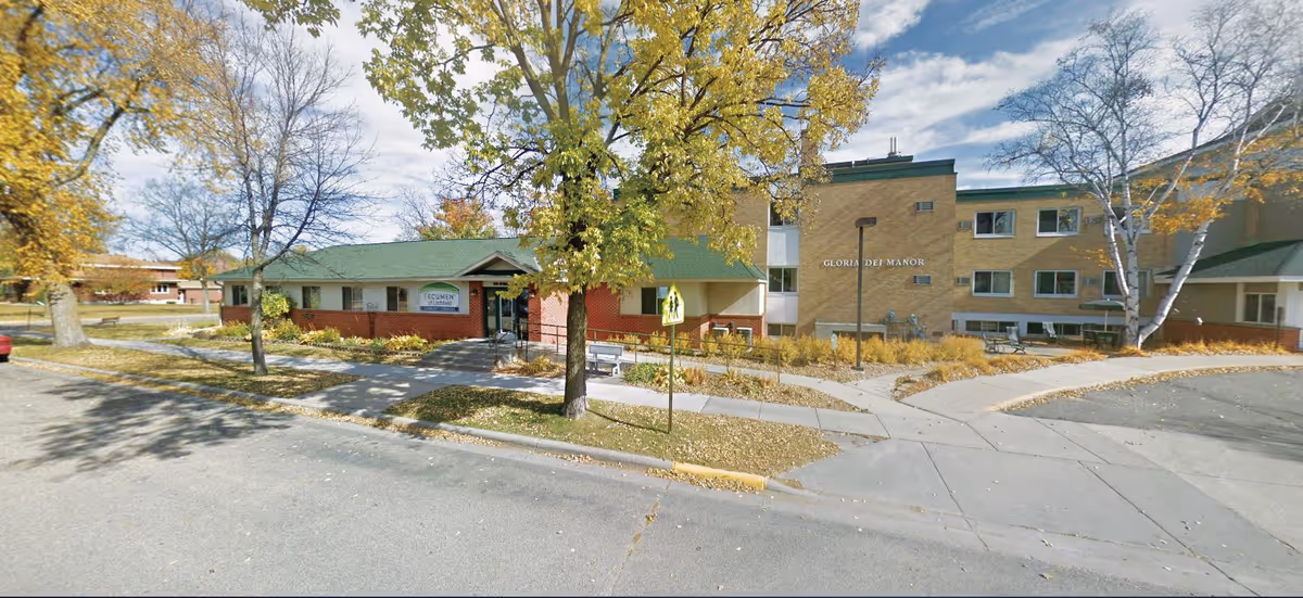 Exterior view of Ecumen Litchfield facility with trees and entrance.