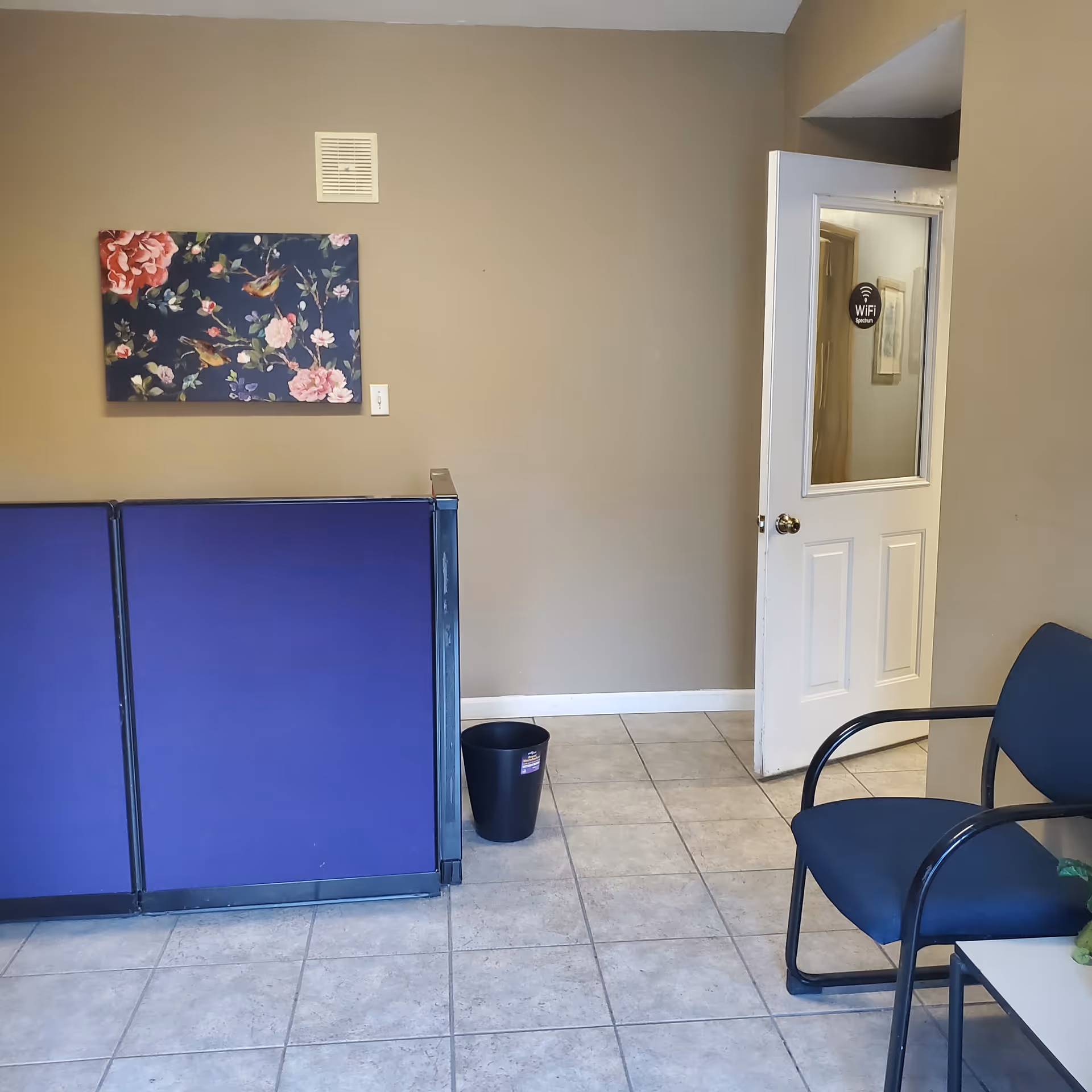 Interior waiting area with purple divider, blue chairs, wall art, and a WiFi door sign.
