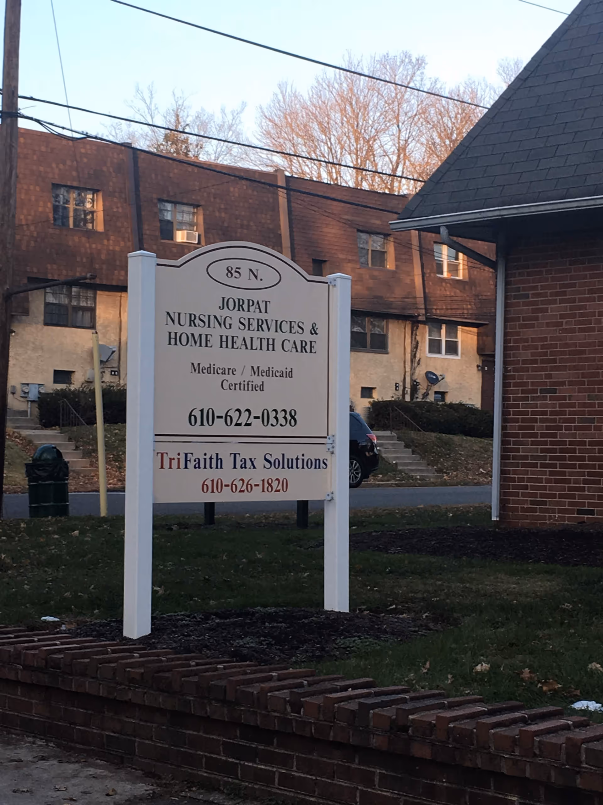 A white sign for Jorpat Nursing Services stands outside a brick building.