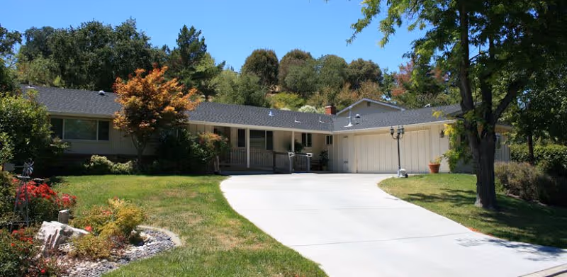 Single-story senior residence with a curved driveway, manicured lawn, and front entrance.