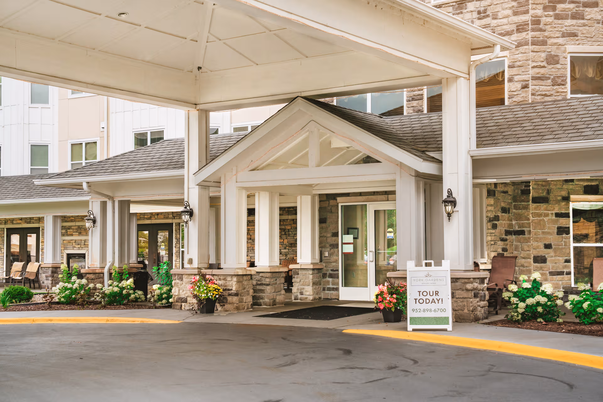 Entrance of York Gardens senior living facility with stone columns and a covered entrance.