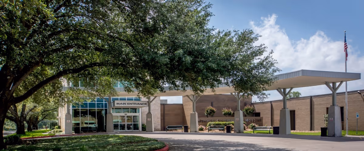 Exterior view of Columbus Community Hospital main entrance with a covered drop-off canopy and flag.