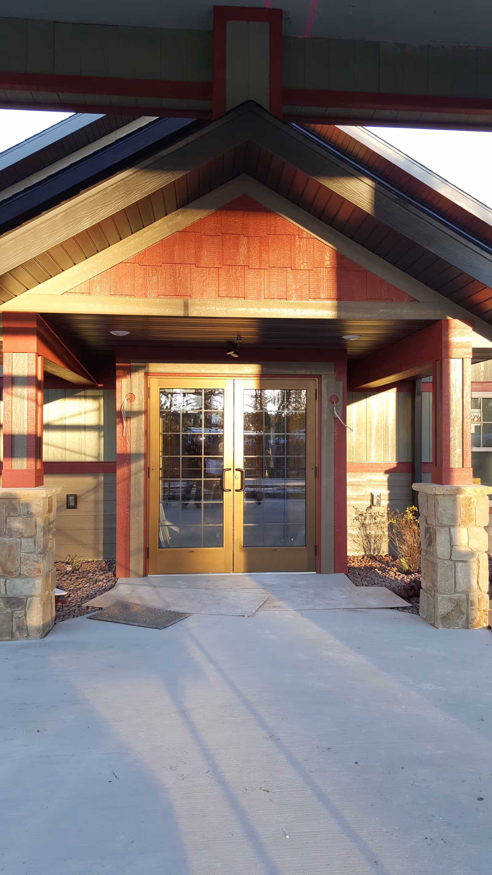 Gold double doors framed by red and stone entrance under a peaked roof.