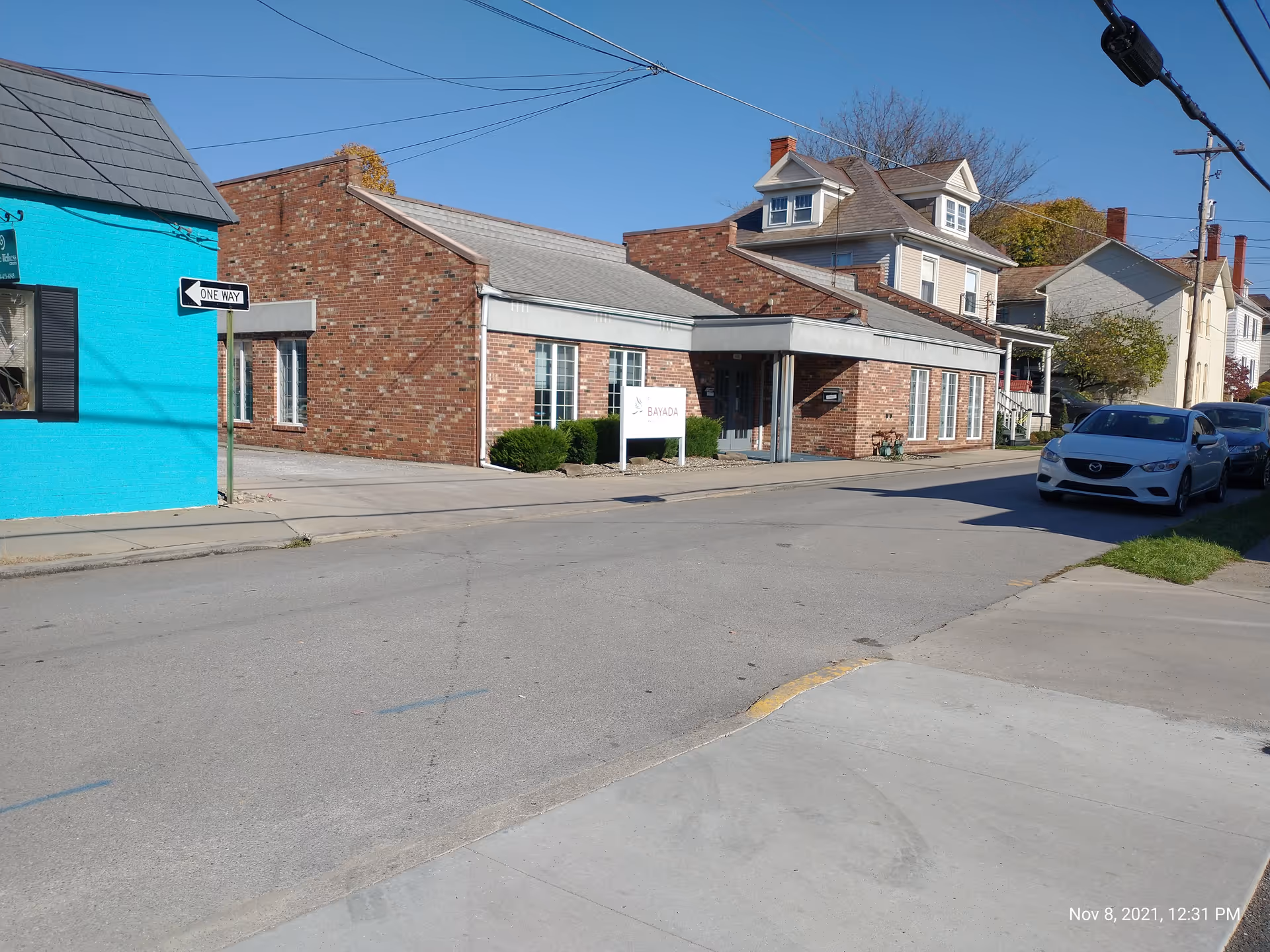 Street view of a brick building labeled BAYADA Pediatrics with parked cars along the curb