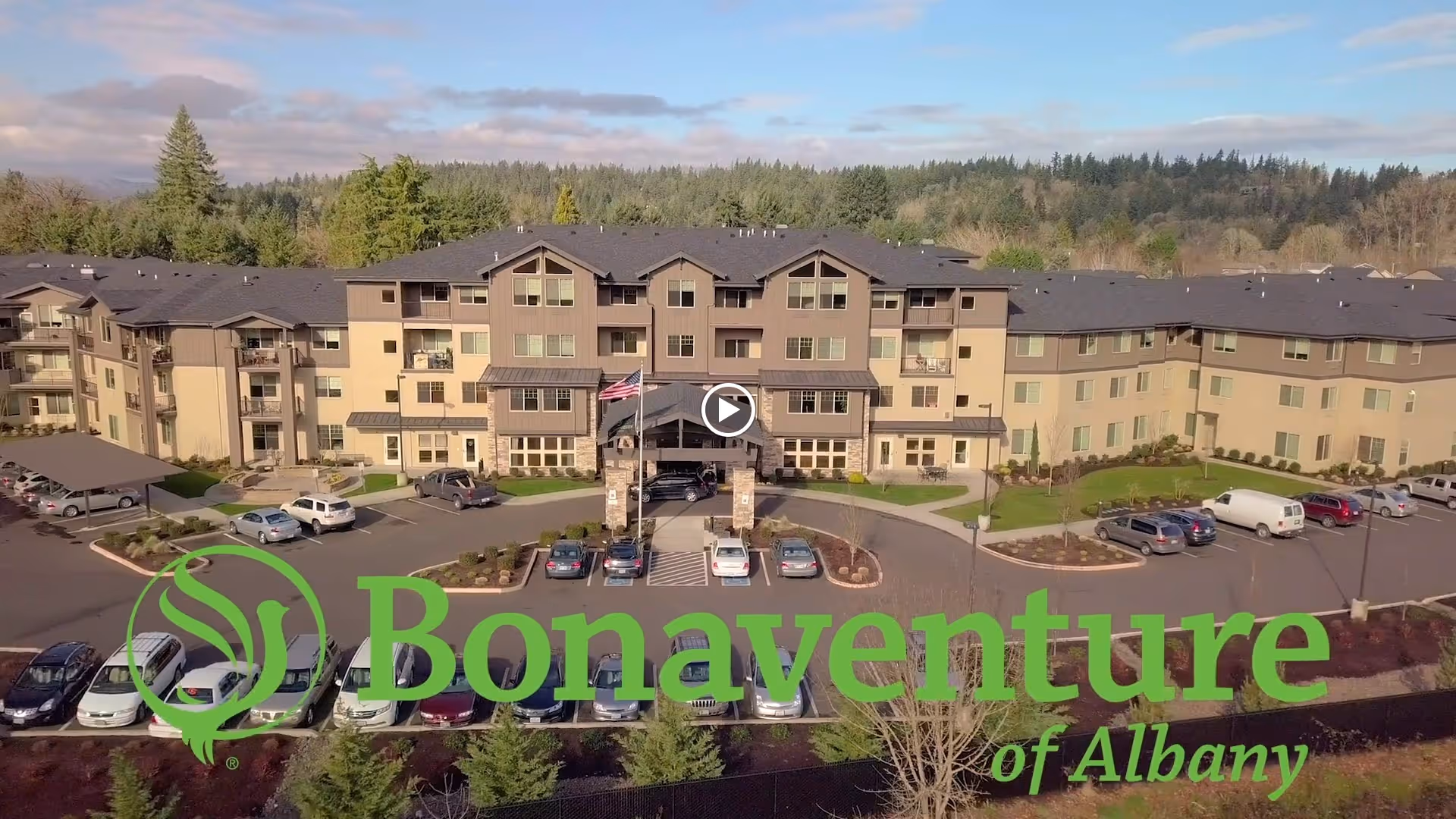 Aerial front view of a multi-story senior living building with parking lot and a large green Bonaventure of Albany logo overlaid.