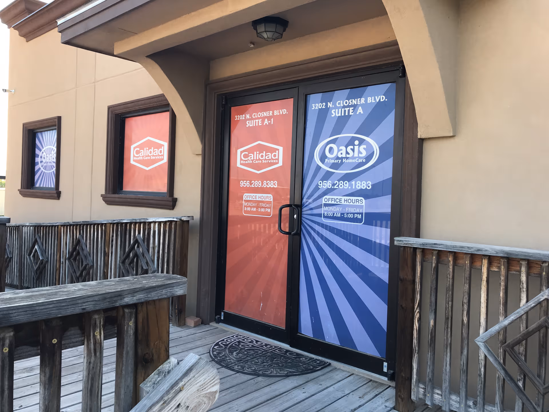 Front entrance of Oasis Primary Home Care with colored glass doors and wooden railing.
