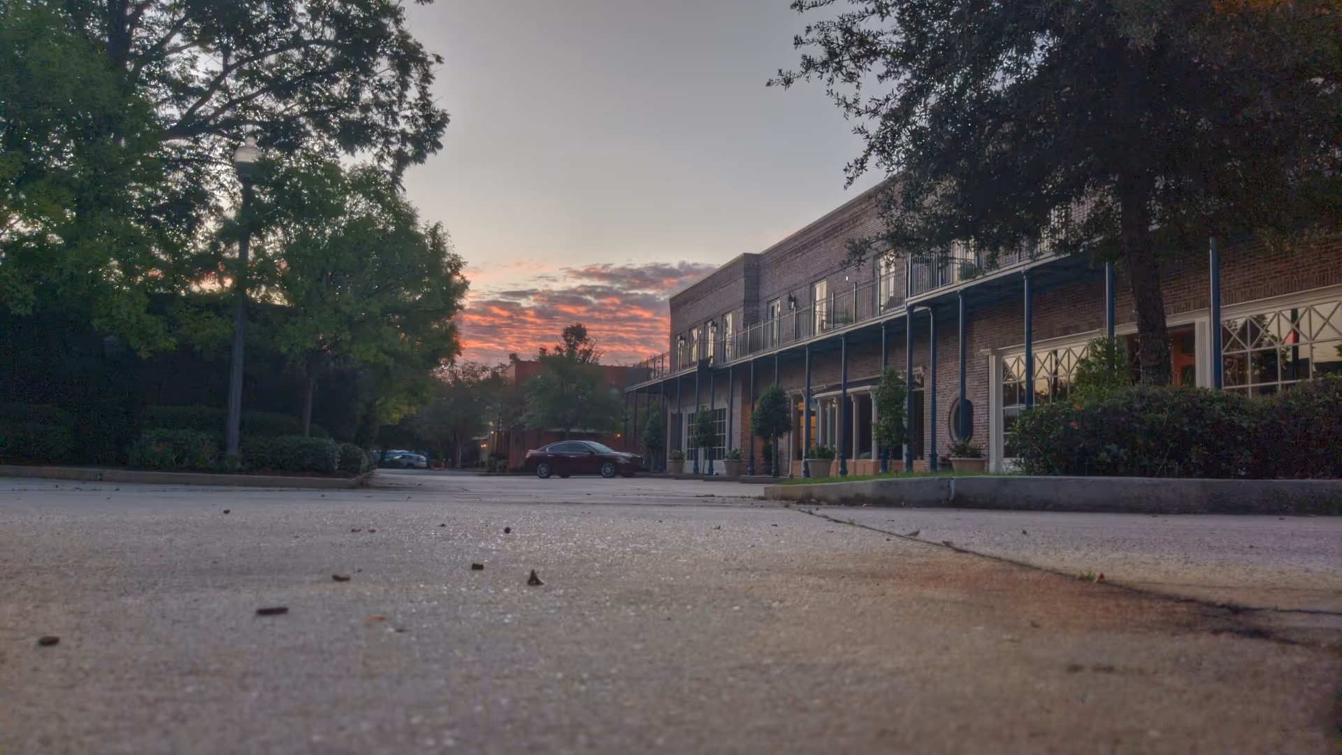 Sunset over a brick senior living facility exterior with a parking lot.