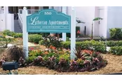 A sign reading Lutheran Apartments sits in a landscaped garden in front of the building.