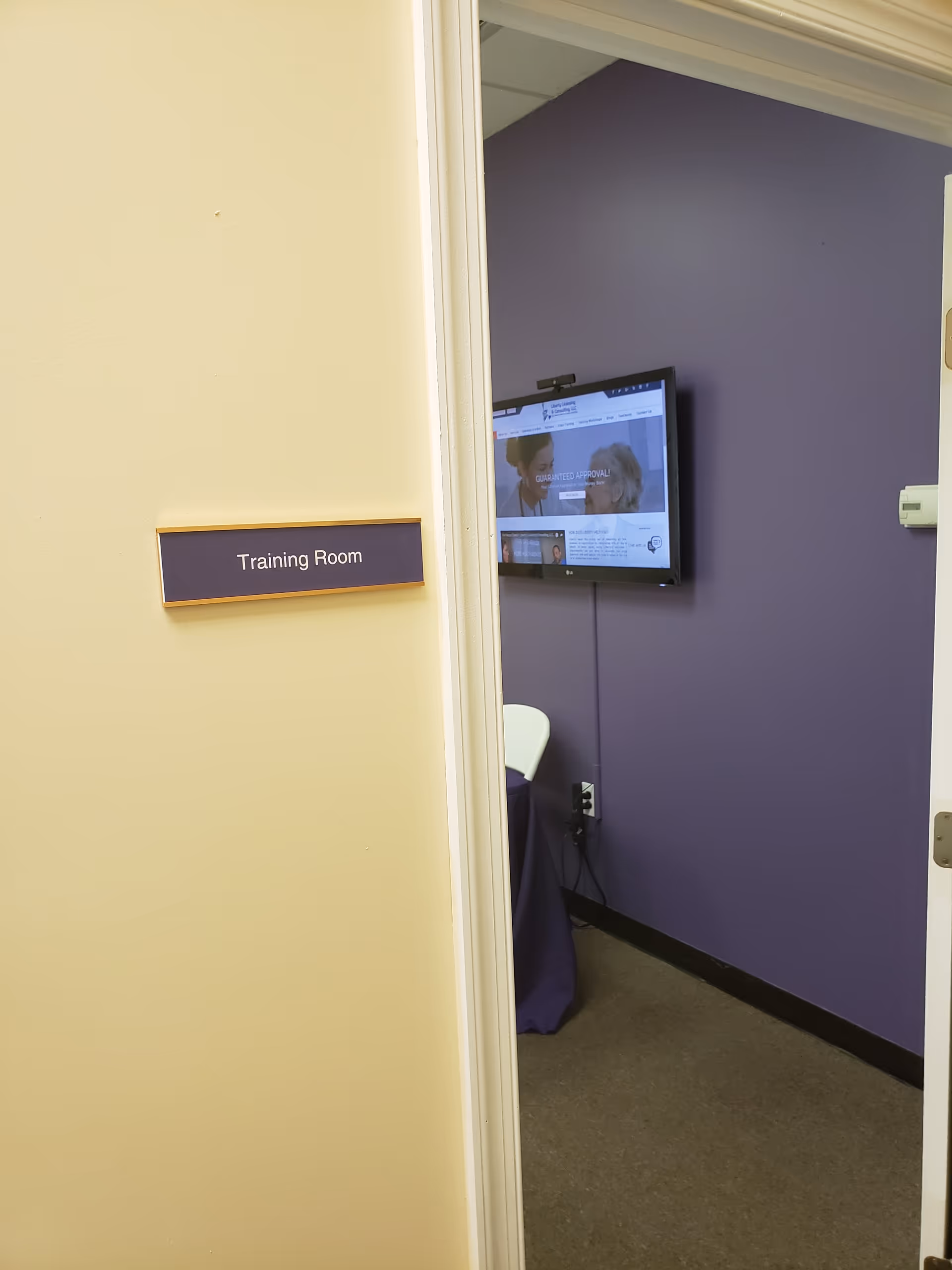 Doorway leads to a Training Room with wall-mounted TV against purple wall.