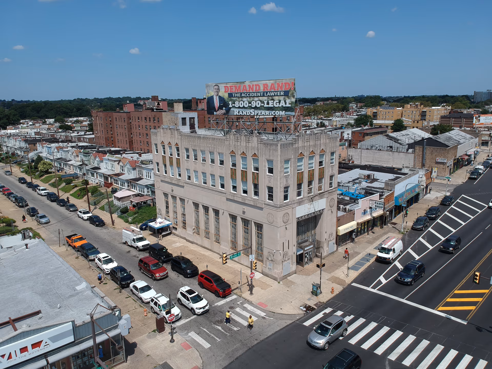 Aerial view of a corner city block featuring a tall gray building with a billboard.