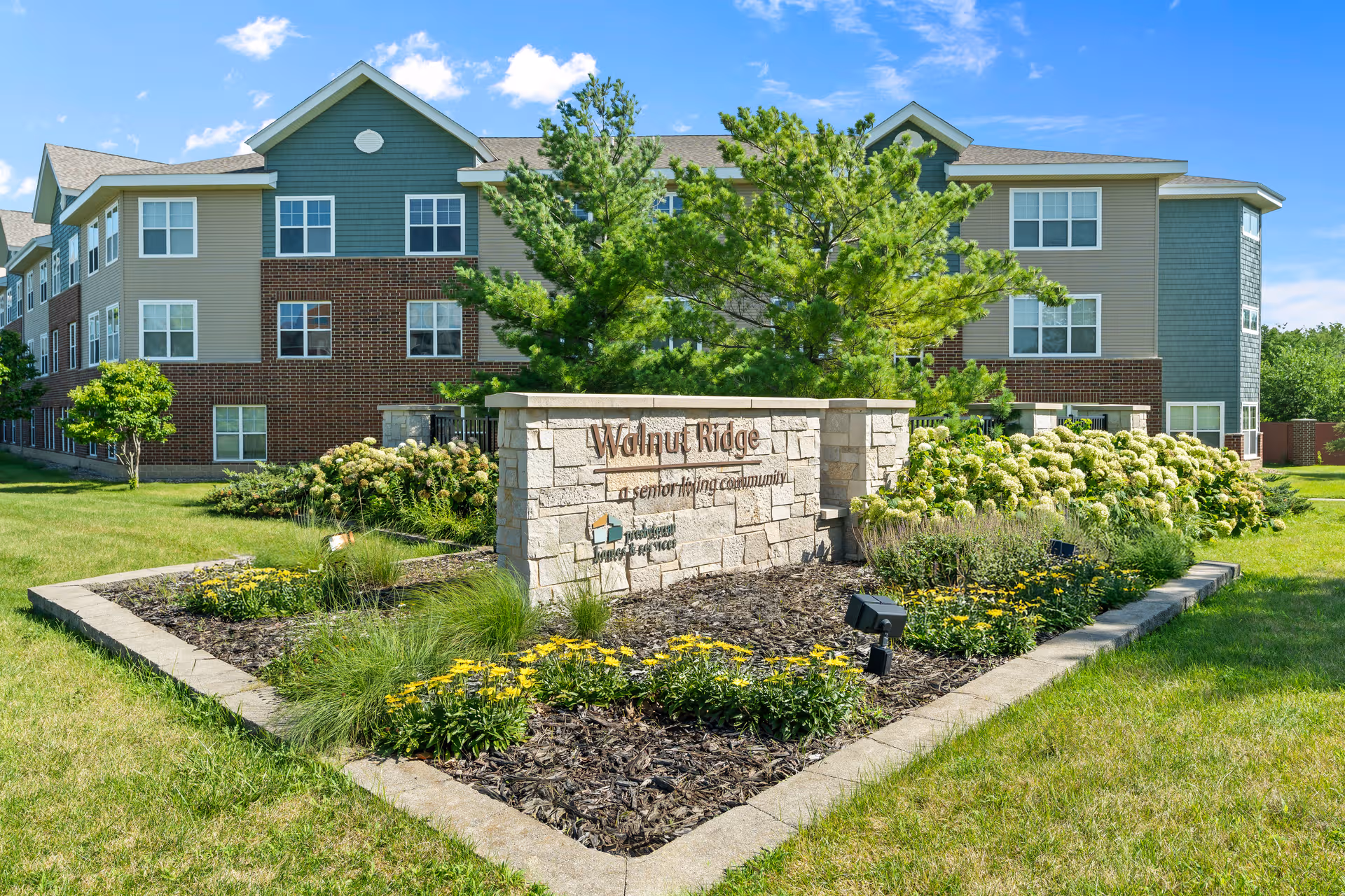 Exterior view of Walnut Ridge senior living facility with landscaped entrance sign.
