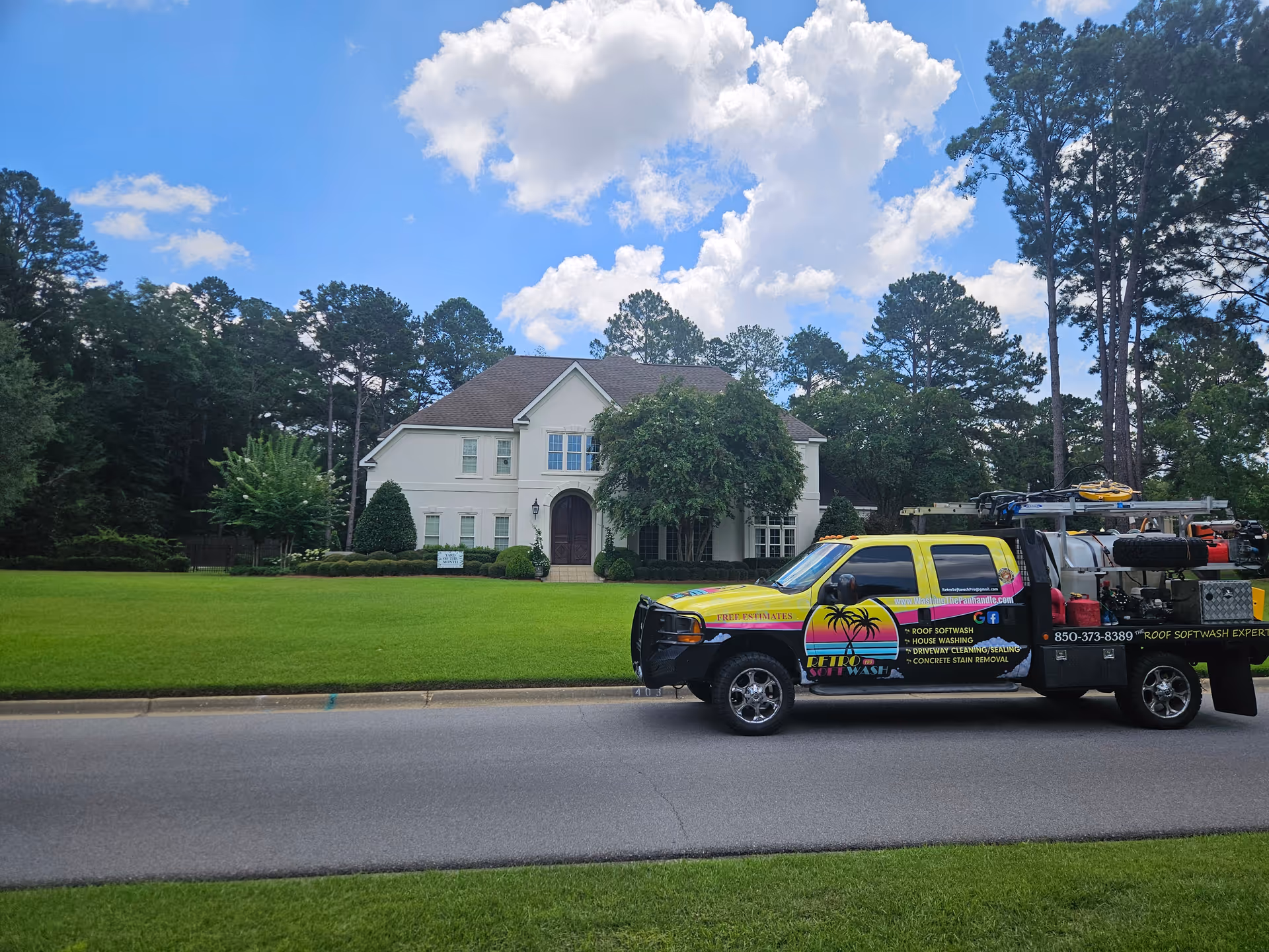White two-story building with manicured lawn and a colorful service truck parked in front.