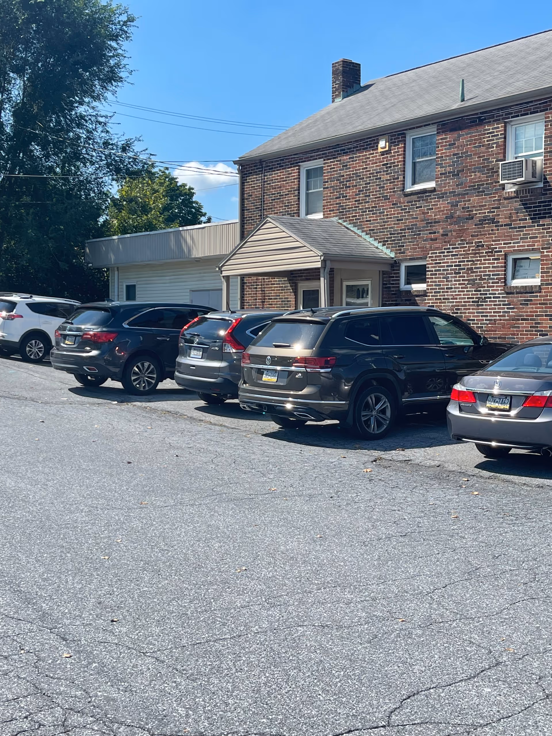 Brick two-story building with a small entrance and parked cars in front.