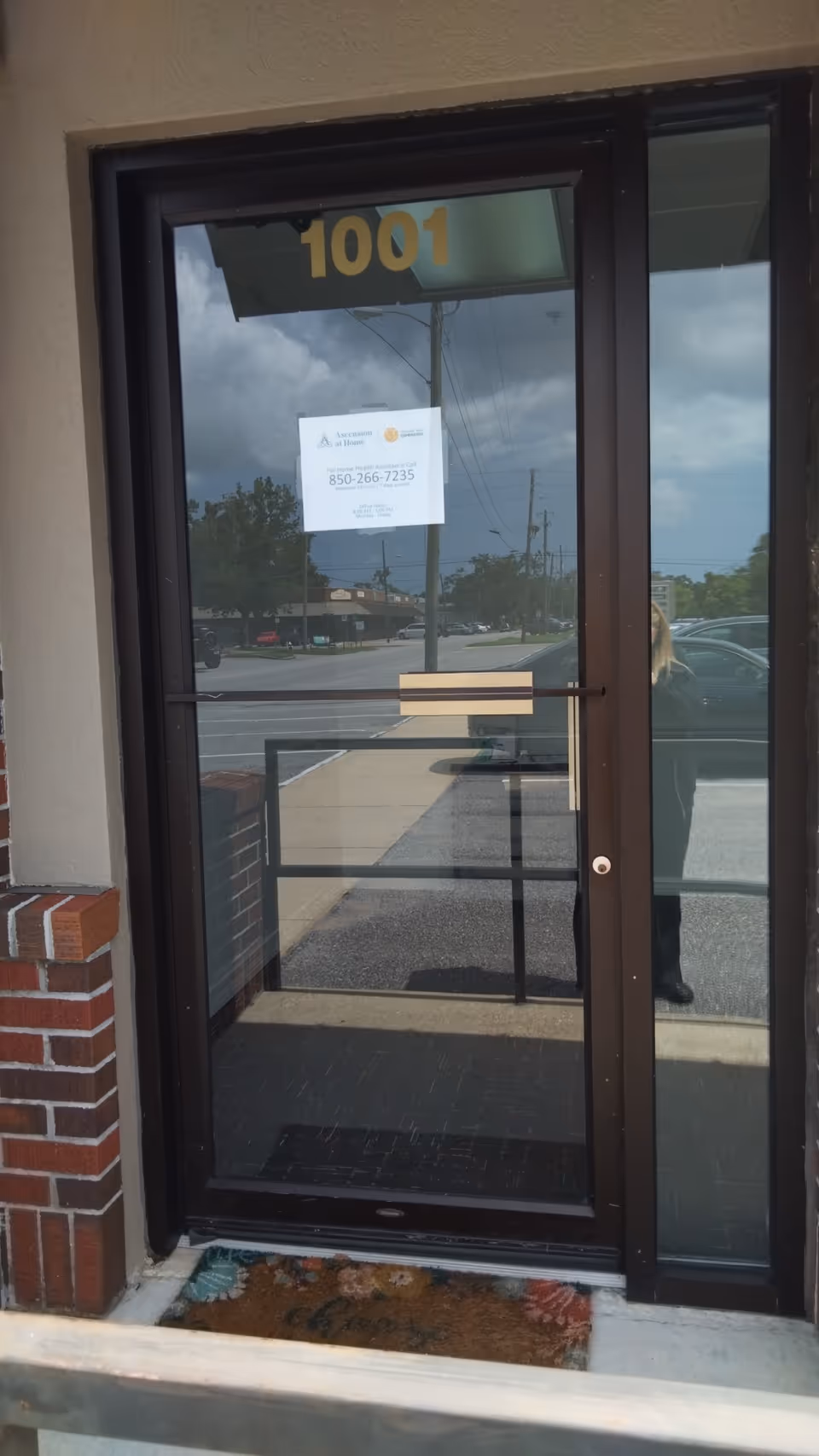 Glass front door labeled 1001 with brick wall and street reflection