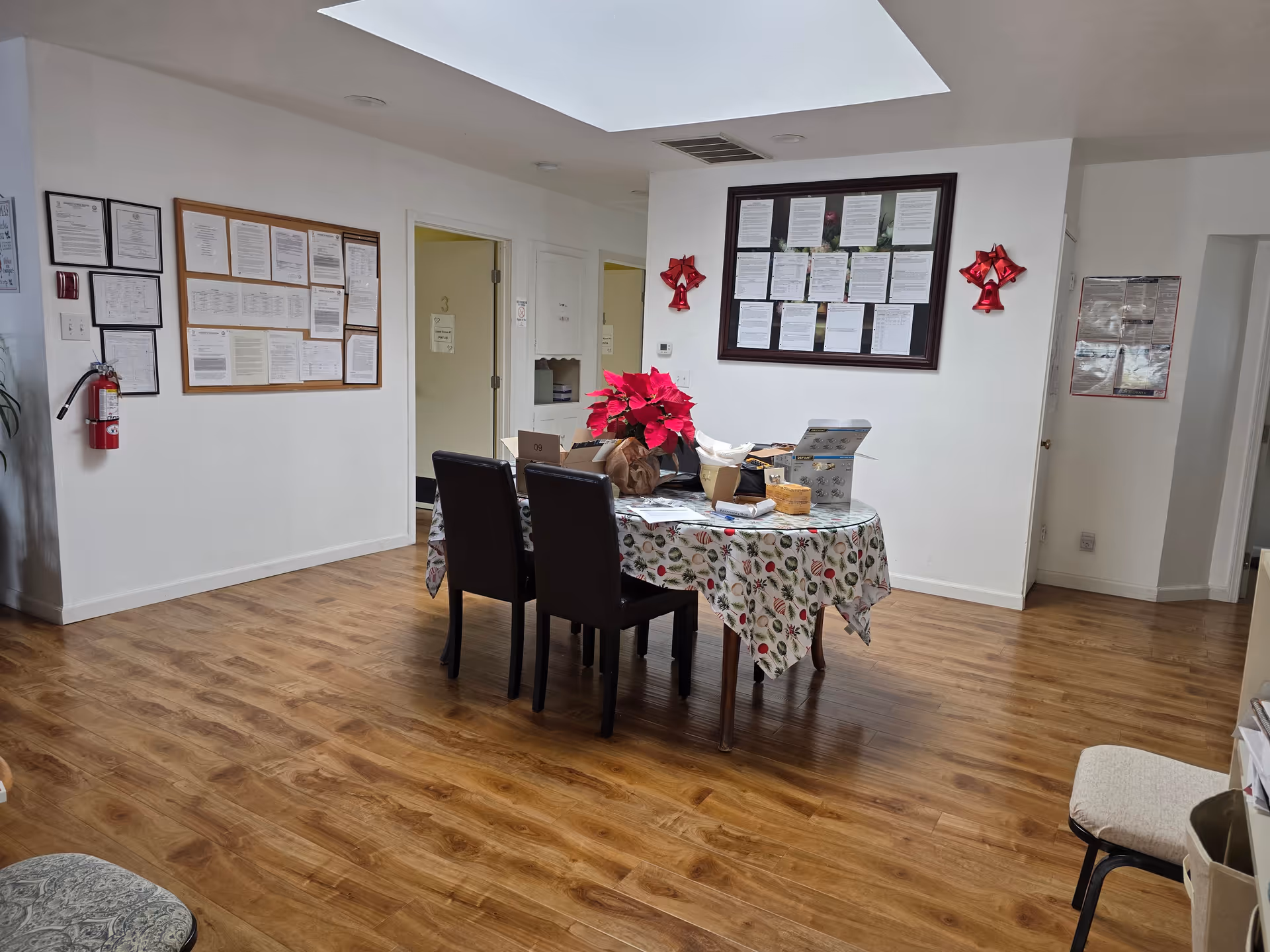 Communal dining area in a senior facility with a table, chairs, and wall notices.