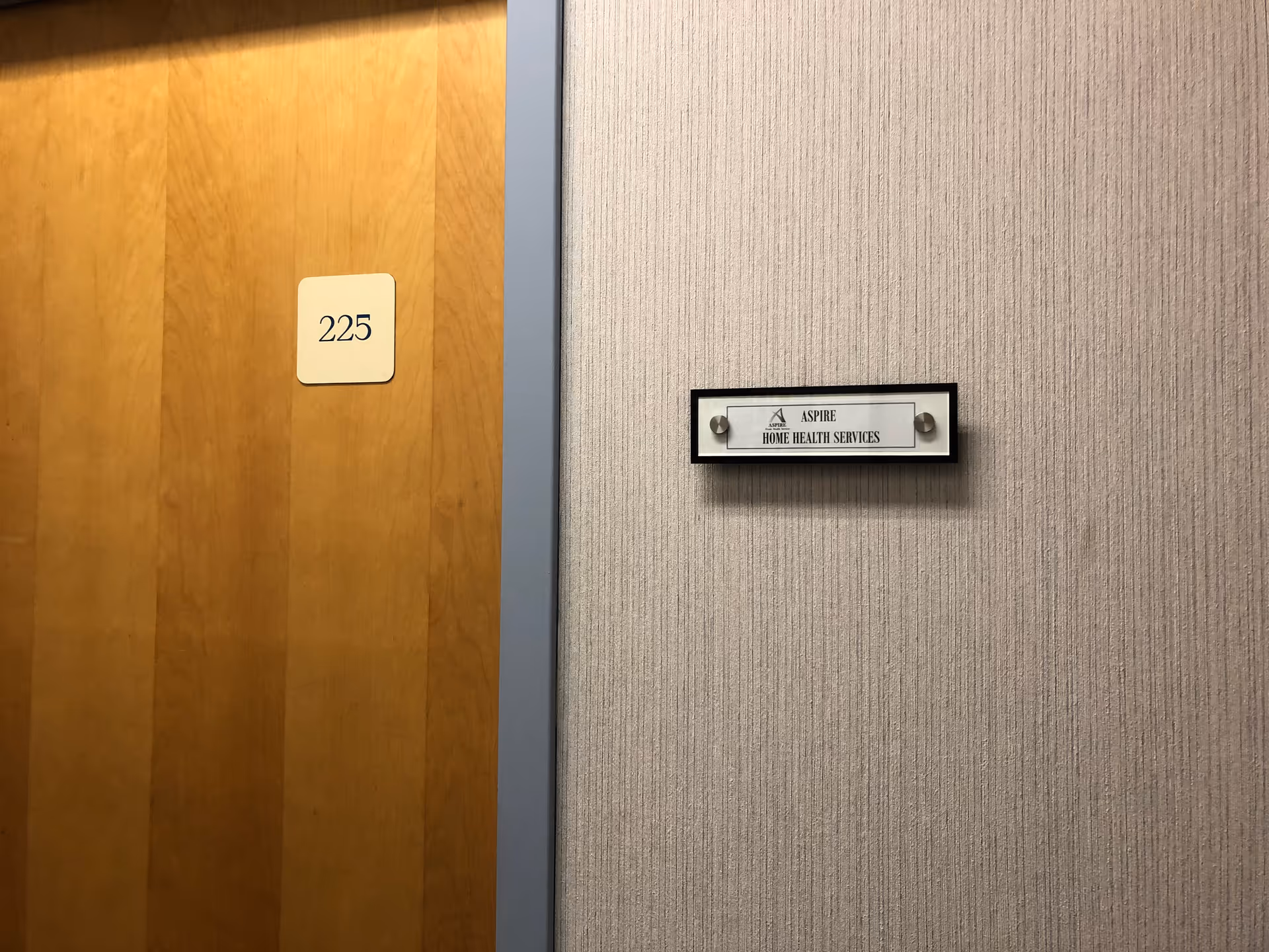Interior hallway with a wooden door labeled 225 and a plaque reading Aspire Home Health Services.